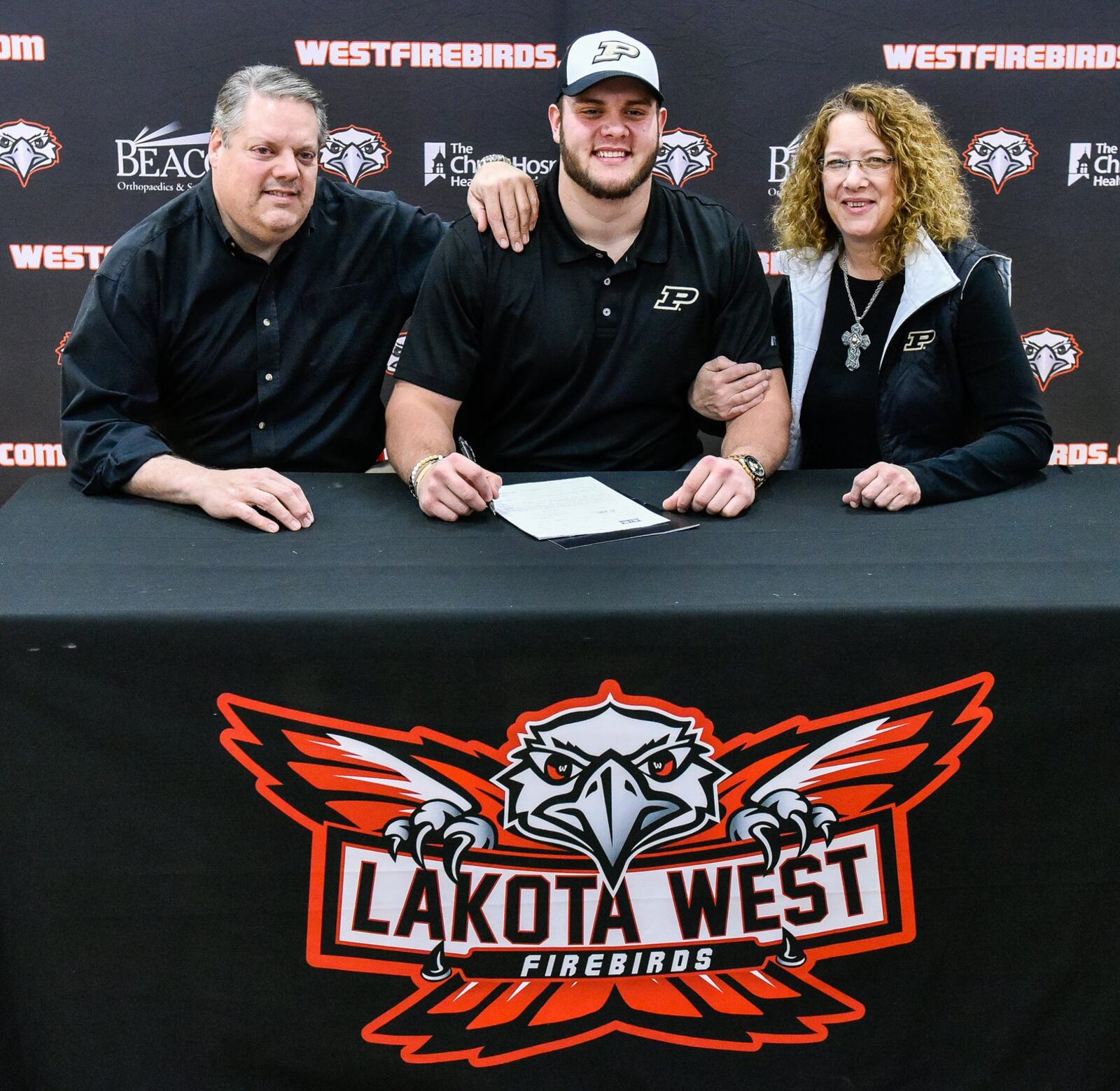 Lakota West’s Steven Faucheux (middle) sits with his parents Debbie and Scott Faucheux during an early National Signing Day ceremony Wednesday afternoon at West. Steven signed with Purdue University. NICK GRAHAM/STAFF