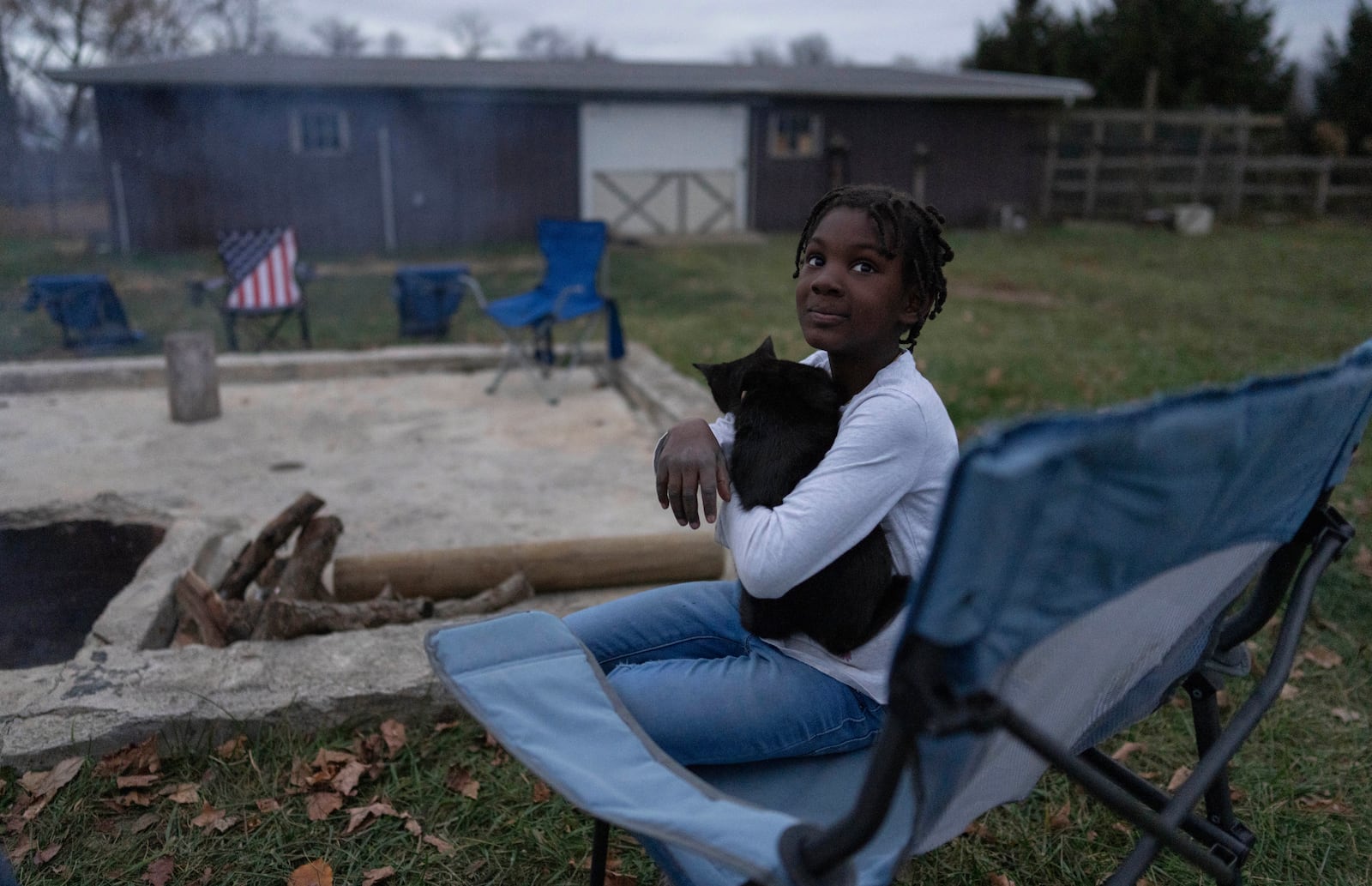 Gianna Young, 7, holds a farm cat Coco before gathering with family and members of their Catholic church to pray the "Patriotic Rosary" for the consecration of the nation and Donald Trump around a bonfire at their home, the night before the election, Monday, Nov. 4, 2024, in Sunbury, Ohio. (AP Photo/Carolyn Kaster)