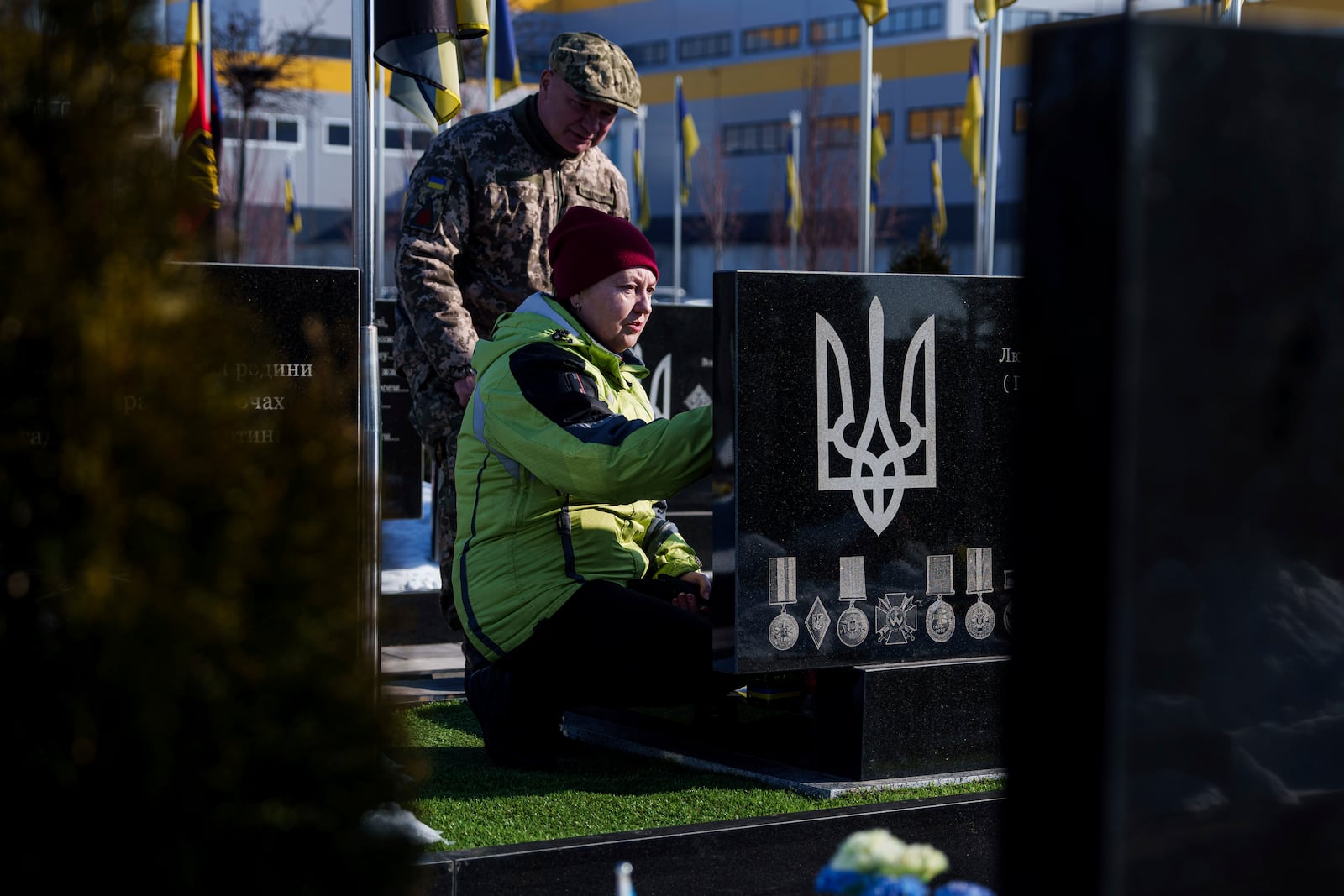 A woman sits in front of a grave of her relative during memorial service for fallen Ukrainian soldiers in Bucha, Ukraine, Feb. 24, 2025. (AP Photo/Evgeniy Maloletka)