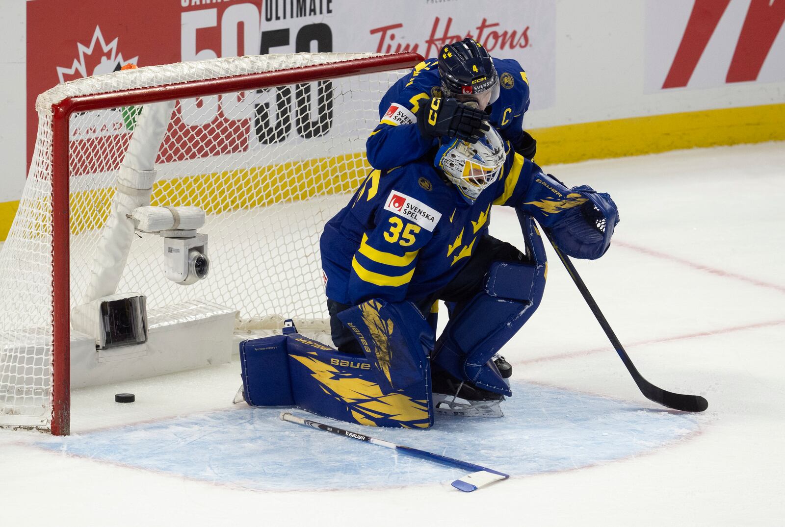 Sweden defenseman Axel Sandin Pellikka(4) hugs goaltender Melker Thelin after losing in overtime against Finland in a semifinal game at the world junior hockey championship, Saturday, Jan. 4, 2025 in Ottawa, Ontario. (Adrian Wyld/The Canadian Press via AP)