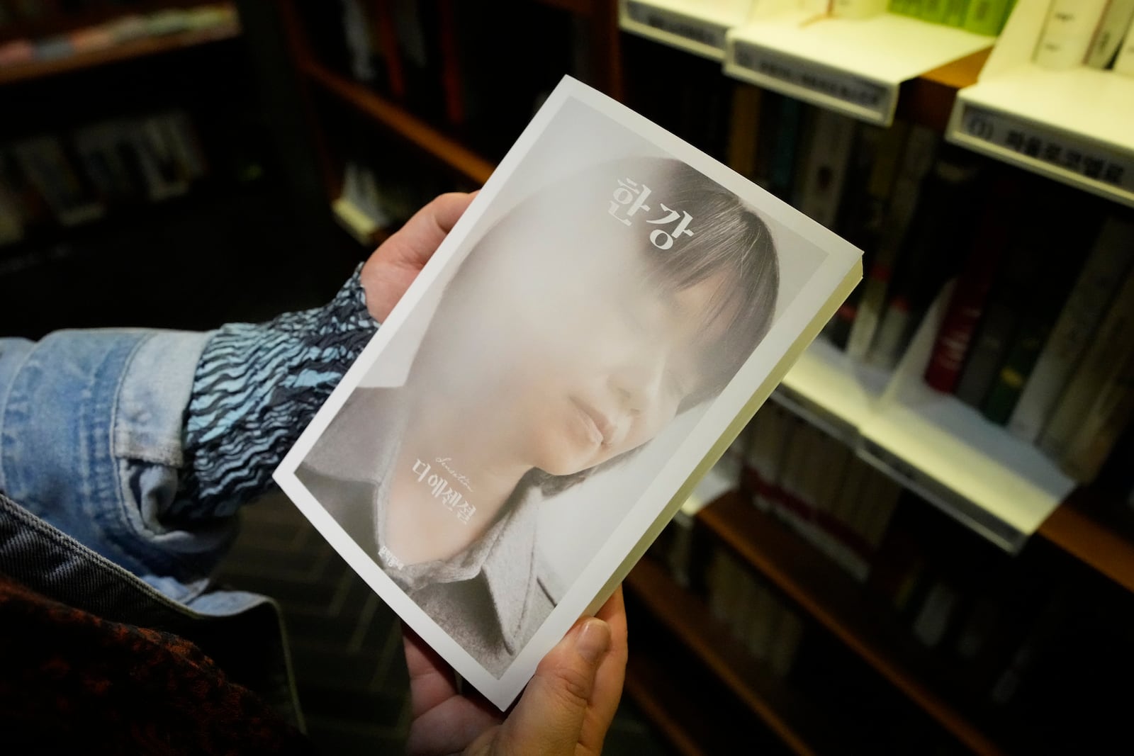 A woman holds a South Korean author Han Kang's book at a bookstore in Goyang, South Korea, Thursday, Oct. 10, 2024. (AP Photo/Lee Jin-man)