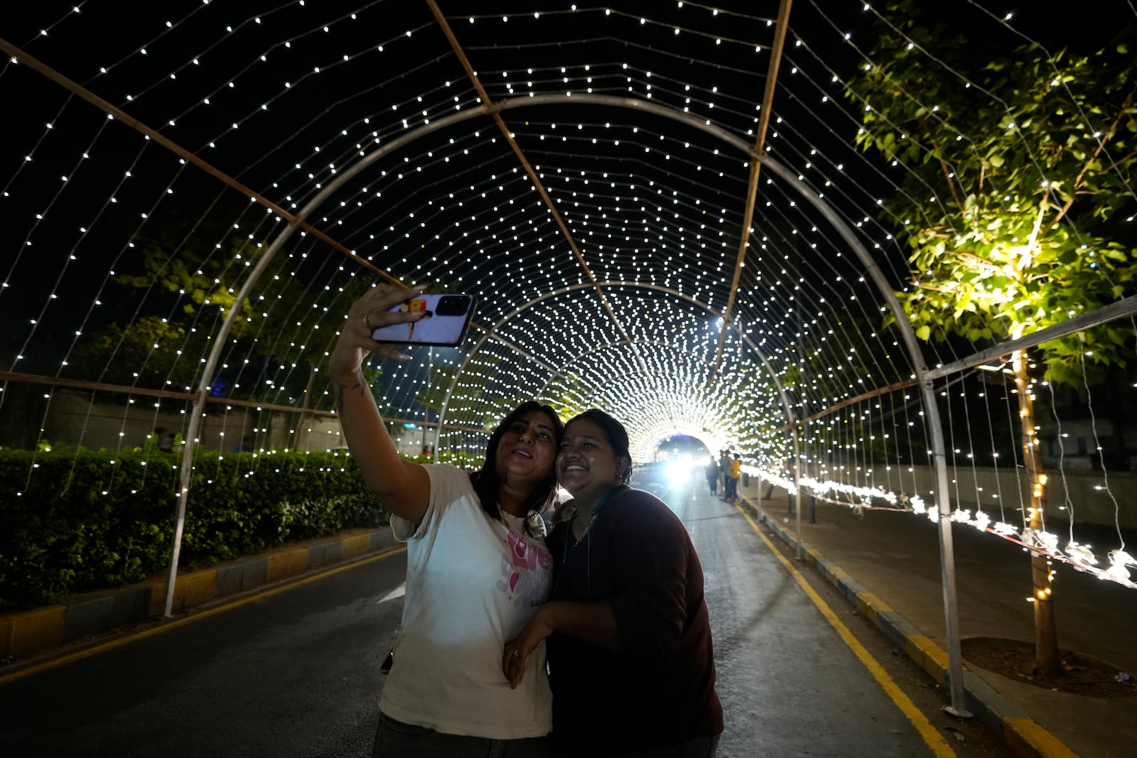 Girls takes selfie on an illuminated road on the Hindu festival of lights Diwali in Ahmedabad, India, Thursday, Oct. 31, 2024. (AP Photo/Ajit Solanki)