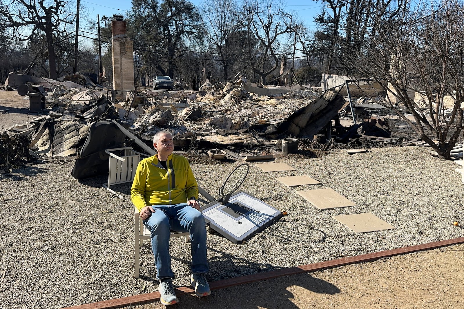 Ryan Pearson, a Los Angeles-based entertainment video editor for The Associated Press, sits in front of his home that was destroyed by the Eaton Fire in Altadena, Calif., Wednesday, Jan. 15, 2025. (AP Photo/Ryan Pearson)