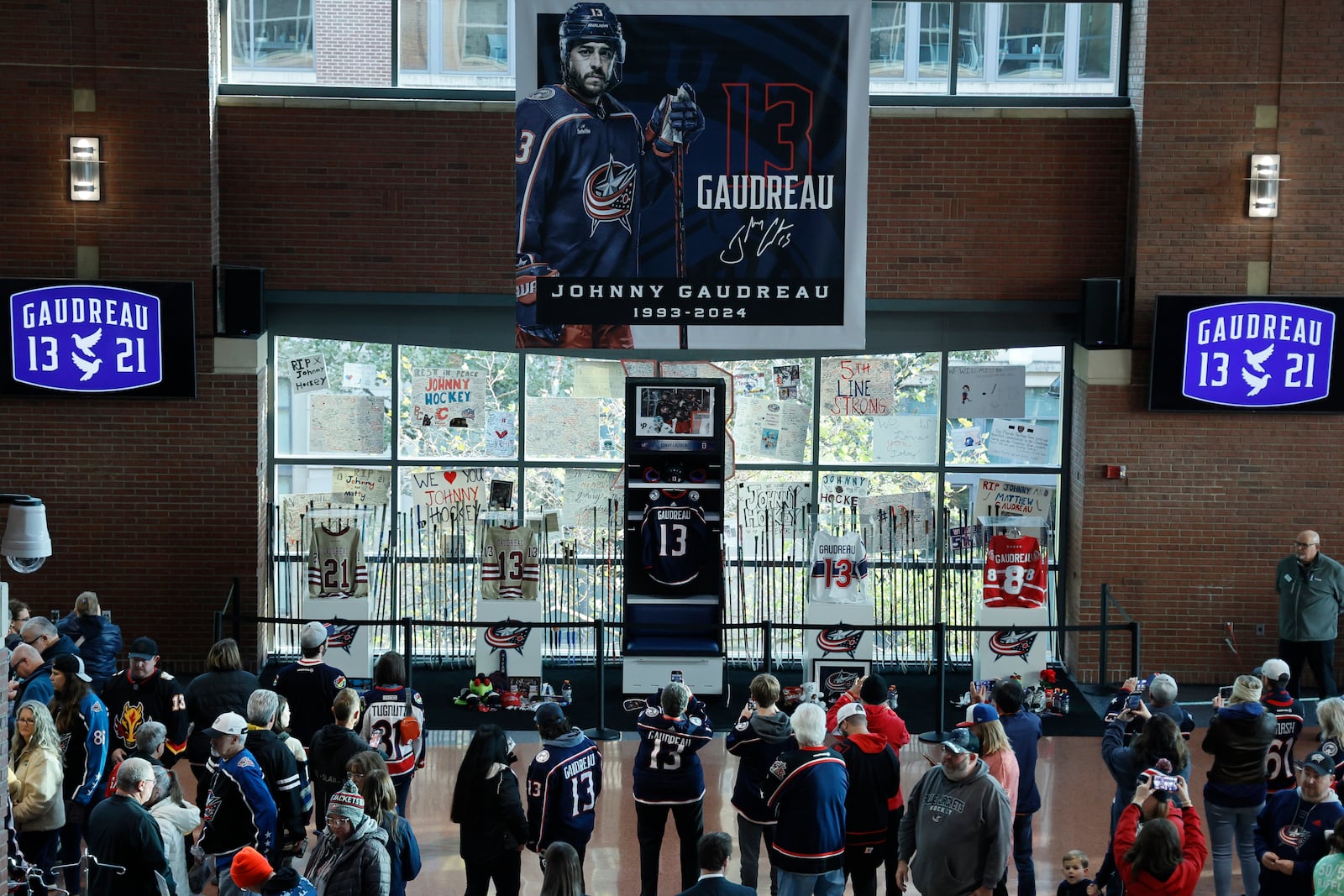 Fans look at a memorial of Columbus Blue Jackets' Johnny Gadreau and his brother Matthew before the start of an NHL hockey game against the Florida Panthers. Tuesday, Oct. 15, 2024, in Columbus, Ohio. (AP Photo/Jay LaPrete)