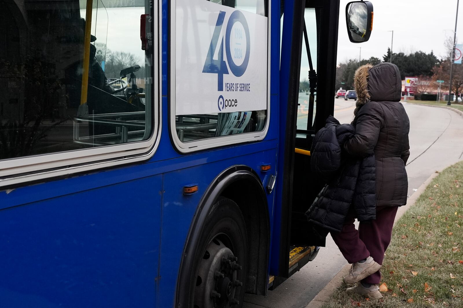 A commuter bundles up as she gets on a bus during cold weather in Wheeling, Ill., Thursday, Dec. 12, 2024. (AP Photo/Nam Y. Huh)