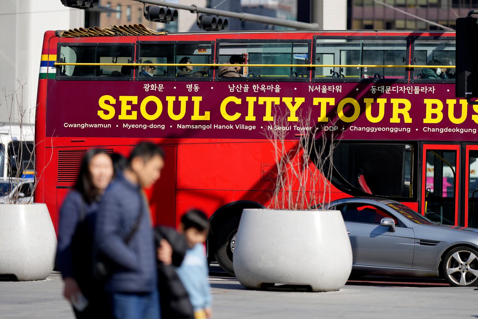 People walk near South Korea's capital Seoul tour bus in Seoul, South Korea, Thursday, Feb. 27, 2025. (AP Photo/Lee Jin-man)