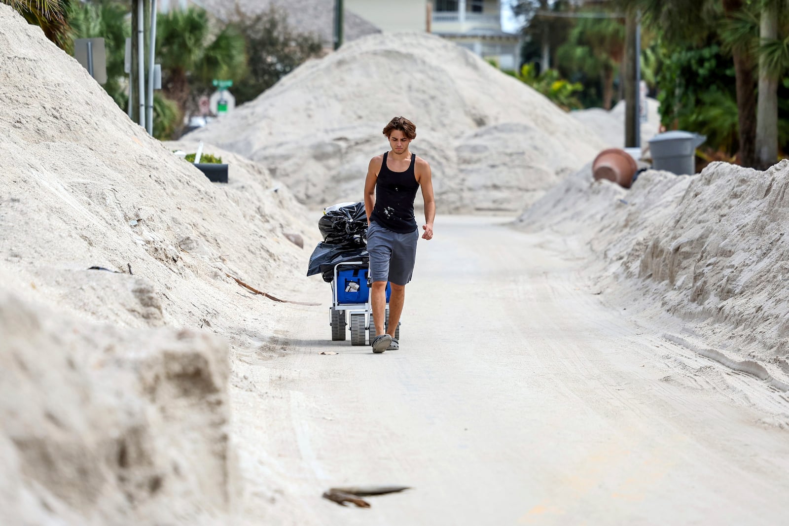 FILE - David DeMeza pulls his belongings through sand-lined streets after Hurricane Helene, Oct. 2, 2024, in Treasure Island, Fla. (AP Photo/Mike Carlson, File)