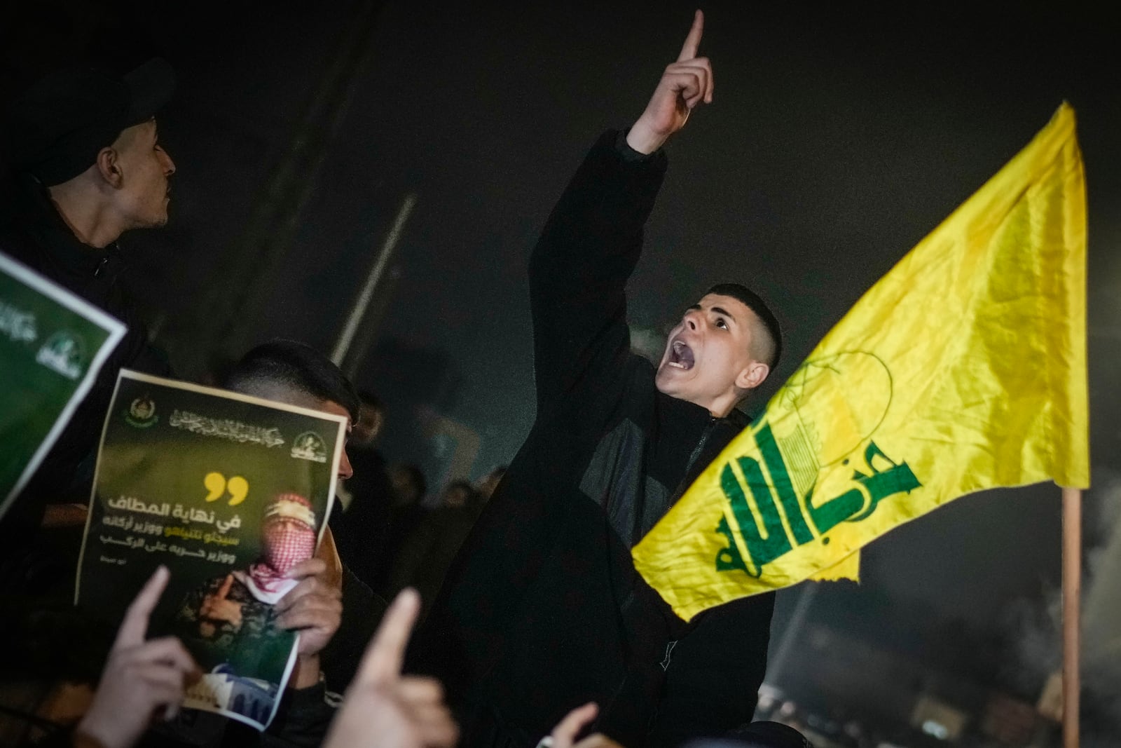 A Palestinian shouts next to a Hezbollah flag as a crowd waits for the arrival of the released Palestinian prisoners in the West Bank city of Beitunia, Sunday, Jan. 19, 2025. (AP Photo/Leo Correa)