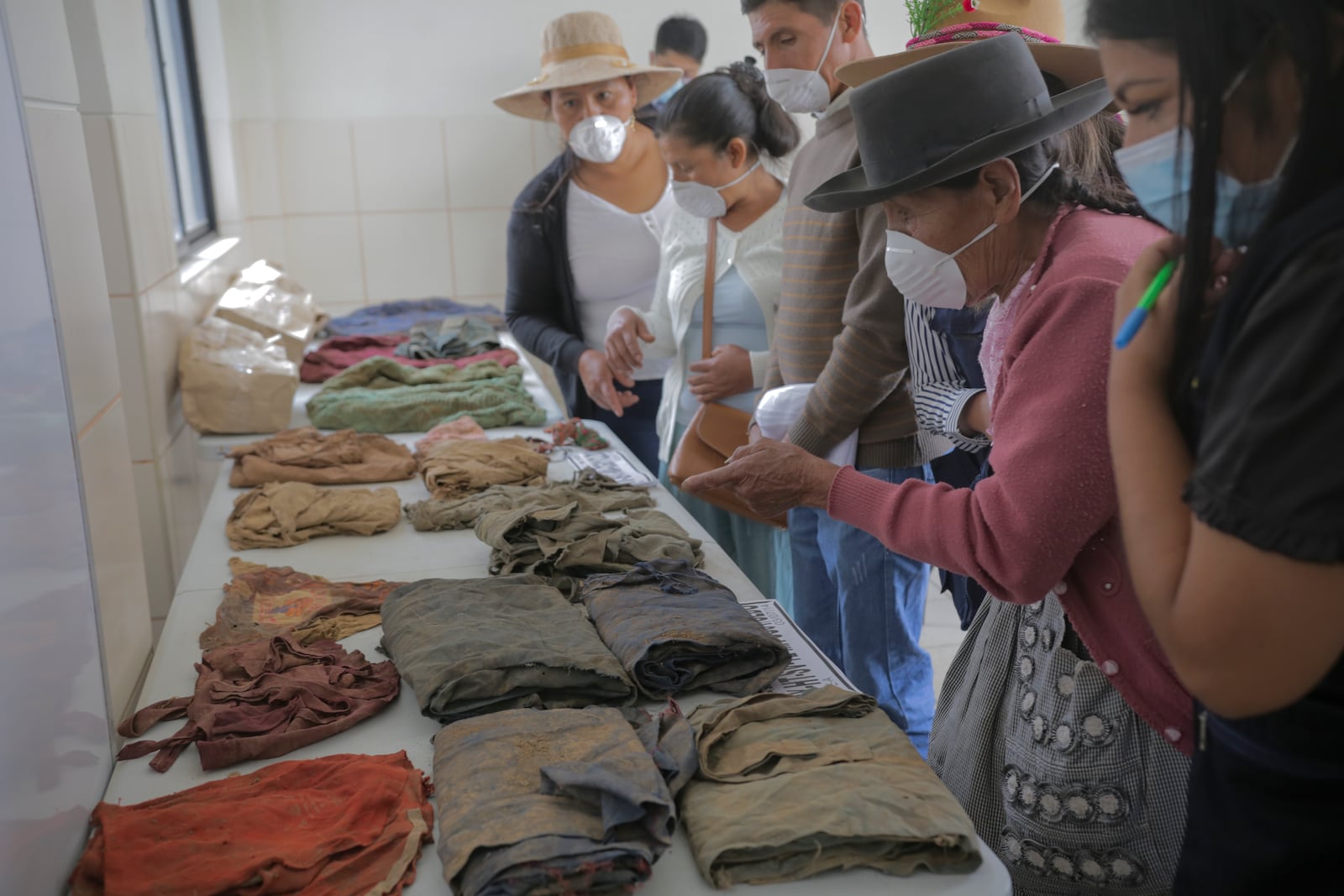 Relatives of people killed during Peru's internal armed conflict (1980-2000) look at clothing found by forensic workers and belonged to their relatives in Ayacucho, Peru, Tuesday, Oct. 22, 2024. (AP Photo/Silvio La Rosa)