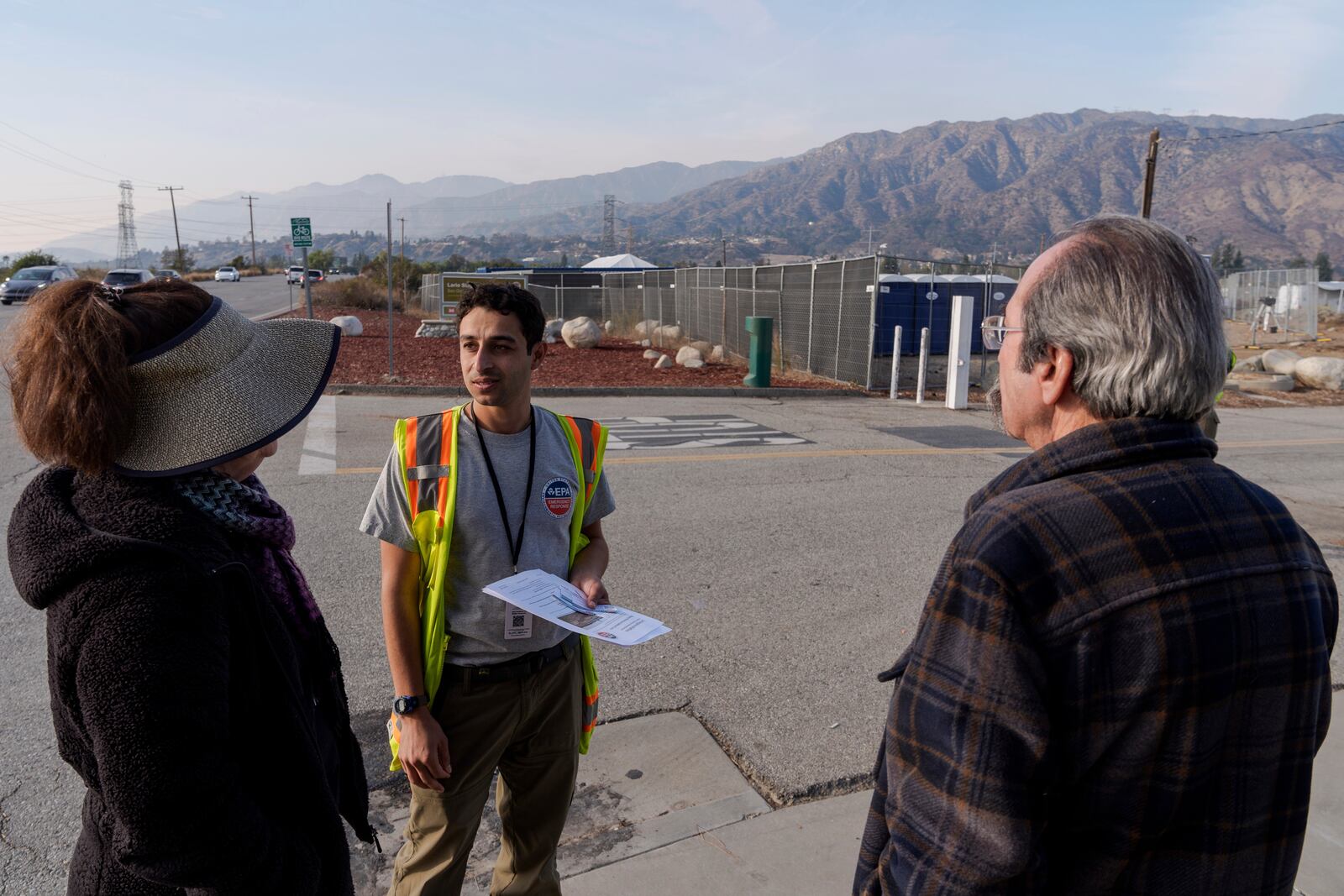 Eric Canteenwala, center, an Environmental Protection Specialist with the Environmental Protection Agency (EPA), talks to Azusa residents who are concerned about the use of Lario Park to temporarily process hazardous materials from the Eaton Fire, in Irwindale, Calif., Friday, Jan. 31, 2025. (AP Photo/Damian Dovarganes)