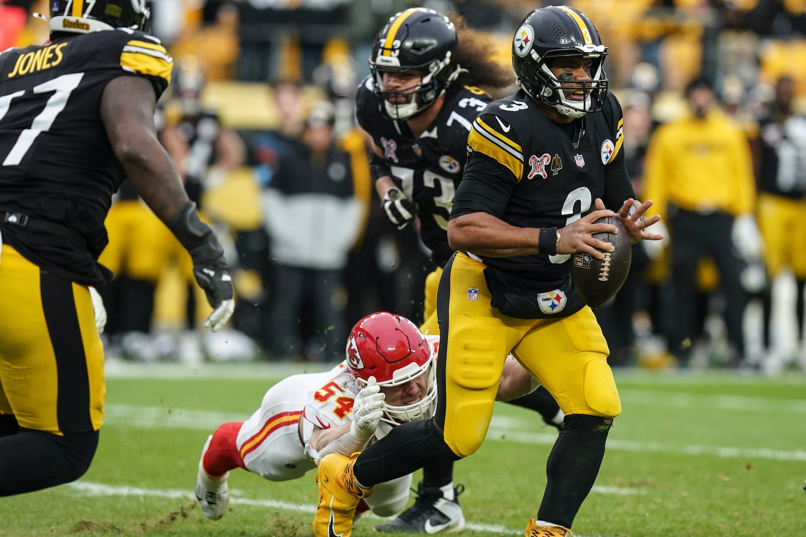 Pittsburgh Steelers quarterback Russell Wilson (3) runs from Kansas City Chiefs linebacker Leo Chenal (54) during the second half of an NFL football game, Wednesday, Dec. 25, 2024, in Pittsburgh. (AP Photo/Matt Freed)