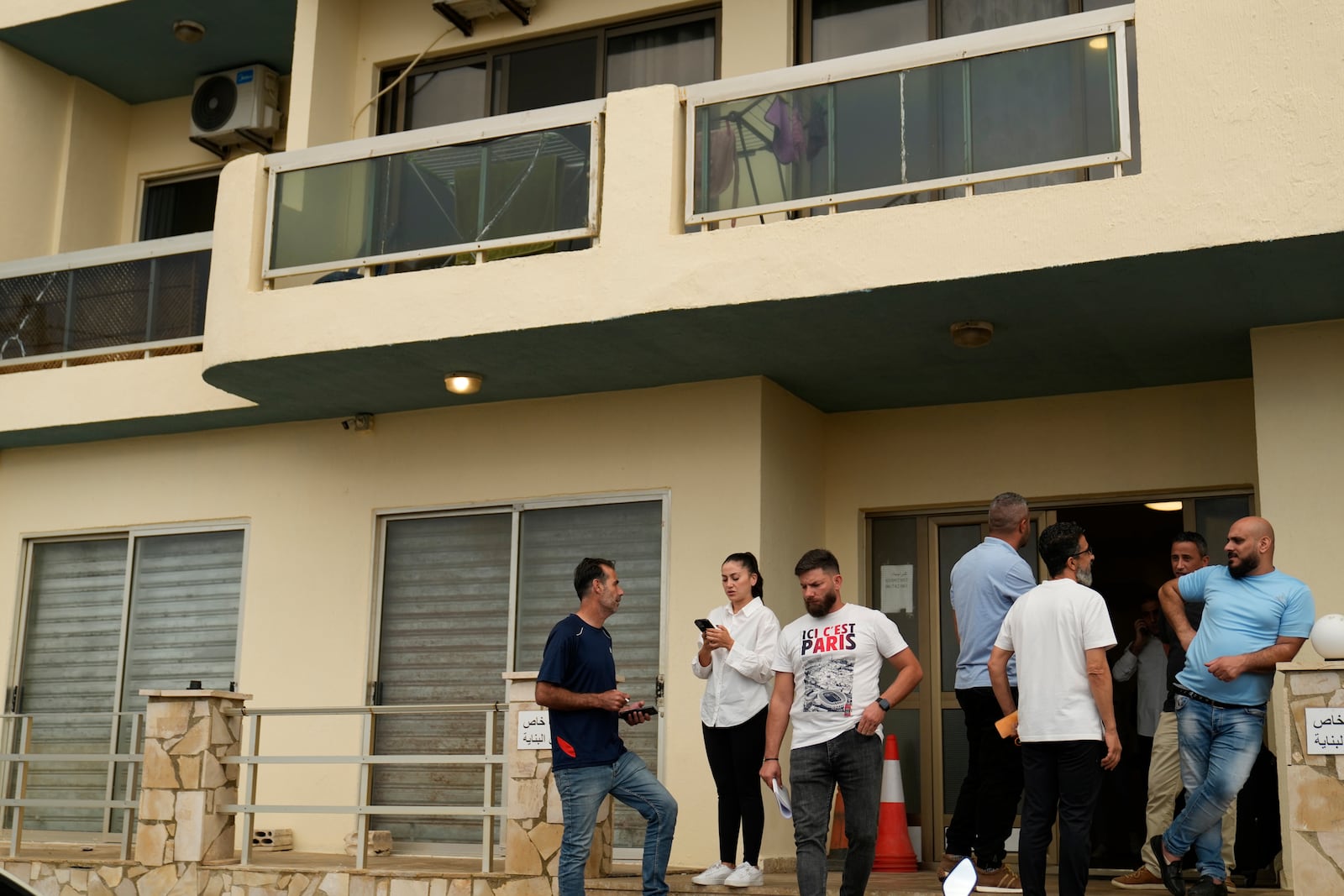 Residents stand at the entrance of a building in Batroun, northern Lebanon, Saturday, Nov. 2, 2024, where Lebanese officials say a ship captain was taken away by a group of armed men who landed on a coast north of Beirut and they're investigating whether Israel was involved. (AP Photo/Hussein Malla)