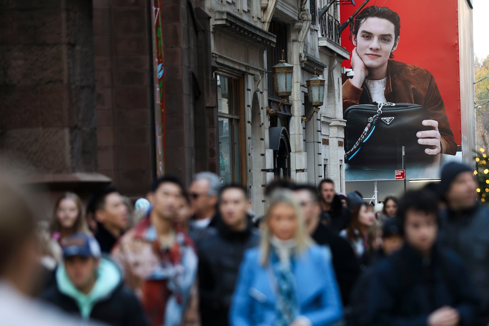 A large advertisement for Prada stands as shoppers walk along Fifth Avenue, Friday, Nov. 29, 2024, in New York. (AP Photo/Heather Khalifa)