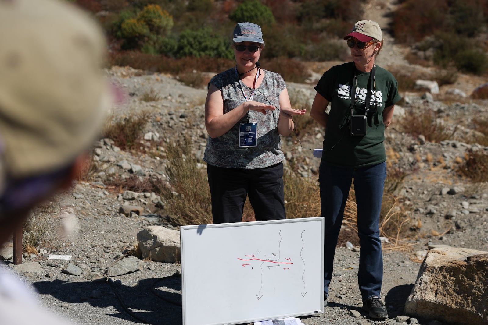 Michele Cook, a professor and geoscientist at the University of Massachusetts Amherst, speaks next to Kate Scharer, a research geologist with the Earthquake Science Center of the U.S. Geological Survey while signing in American Sign Language during an accessible field trip to the San Andreas Fault organized by the International Association of Geoscience Diversity Thursday, Sept. 26, 2024, in San Bernadino, Calif. Cooke is also partially deaf. (AP Photo/Ryan Sun)