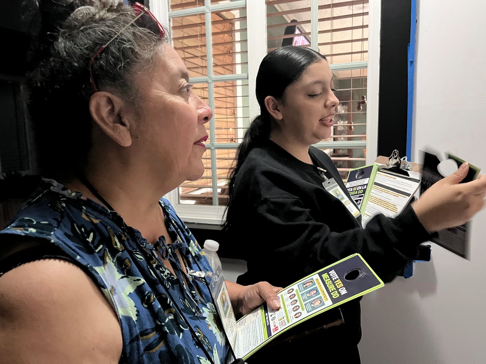 Genesis Lopez, 21, and her mother Nancy Morales, 51, left, speak with residents of a Santa Ana neighborhood on Wednesday, Oct. 23, 2024, about Measure DD, which would allow noncitizens to vote in local elections. (AP Photo/Jaimie Ding)