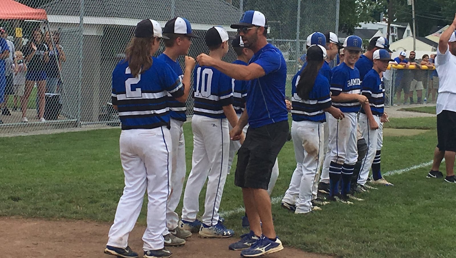 Hamilton West Side coach Ken Coomer congratulates his players, including Jaycee Taylor (2), after Saturday’s 15-4 win over Canfield in the Ohio Little League 12-year-old baseball tournament championship game at Ford Park’s Robert S. Hoag Field in Maumee. RICK CASSANO/STAFF