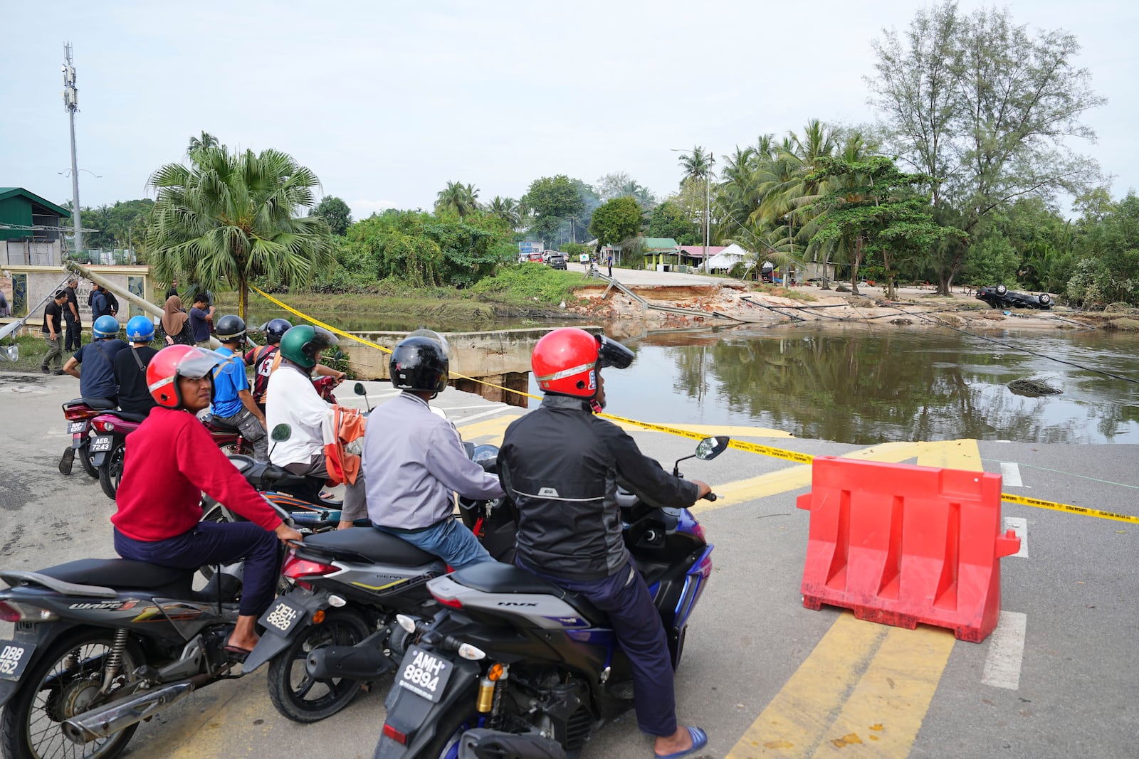 Motorists survey a road damaged by a flood in Tumpat, on the outskirts of Kota Bahru in Kelantan state on the east coast of Malaysia, Tuesday, Dec. 3, 2024. (AP Photo/Vincent Thian)