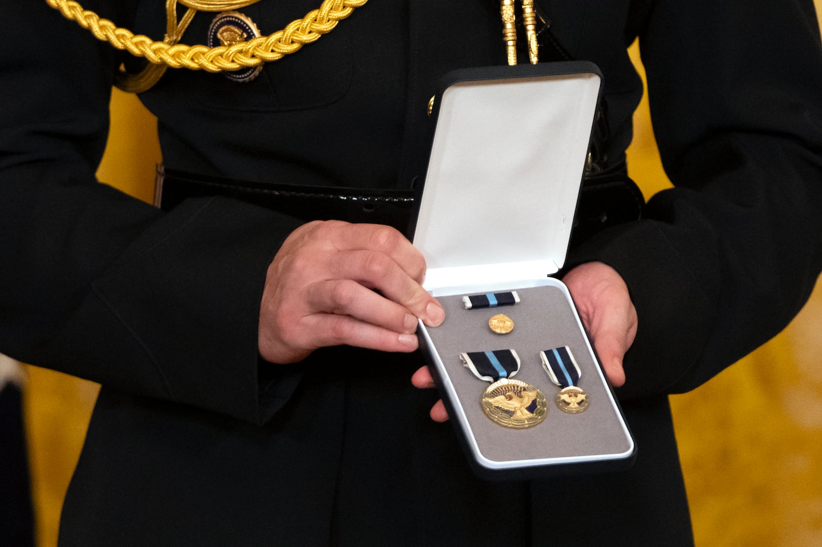 An official holds medals during an event for President Joe Biden to award the Presidential Citizens Medal to recipients in the East Room at the White House, Thursday, Jan. 2, 2025, in Washington. (AP Photo/Mark Schiefelbein)