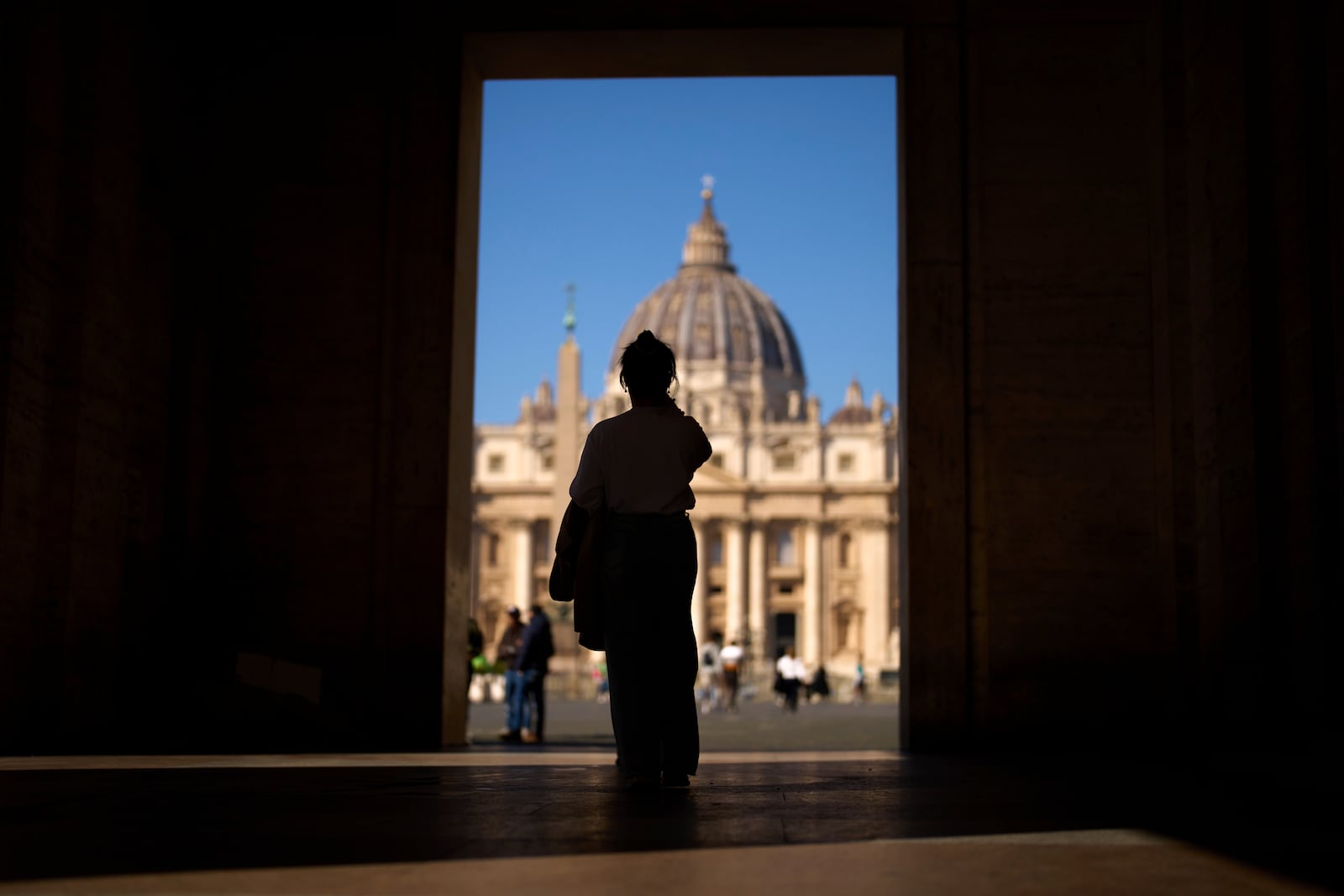 A woman takes photographs of St. Peter's Square at the Vatican, Thursday, March 6, 2025. (AP Photo/Francisco Seco)