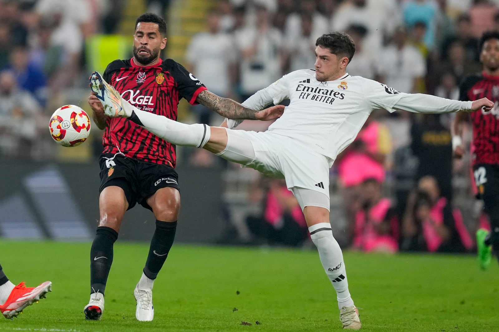 Real Madrid's Federico Valverde, right, is challenged by Mallorca's Omar Mascarell during the Spanish Super Cup semifinal soccer match between Real Madrid and Mallorca at the King Abdullah Stadium in Jeddah, Saudi Arabia, Thursday, Jan. 9, 2025. (AP Photo/Altaf Qadri)