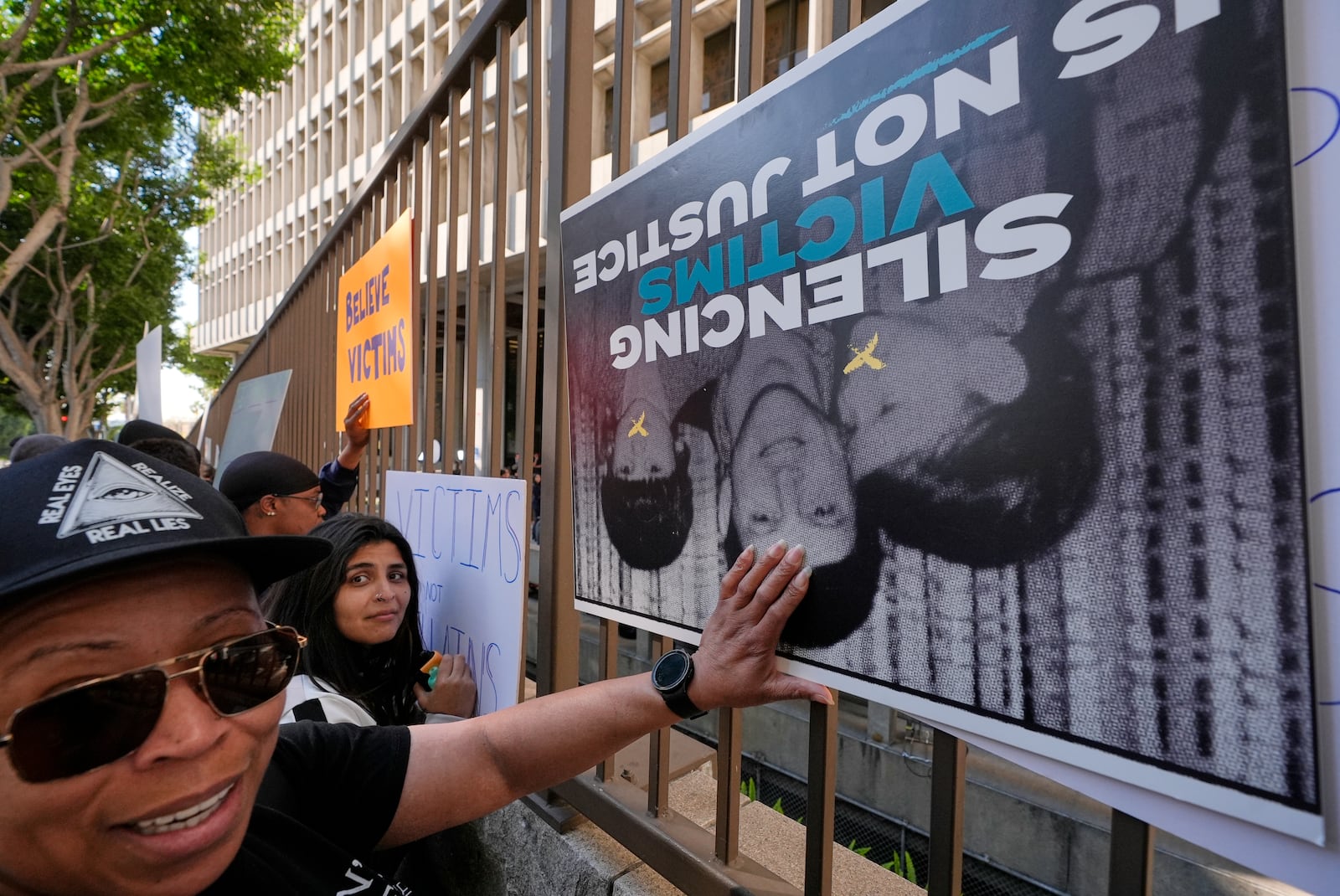 Supporters place signs on a fence outside of the Clara Shortridge Foltz Criminal Justice Center during a press conference regarding developments in the Menendez brothers case Thursday, March 20, 2025, in Los Angeles. (AP Photo/Damian Dovarganes)