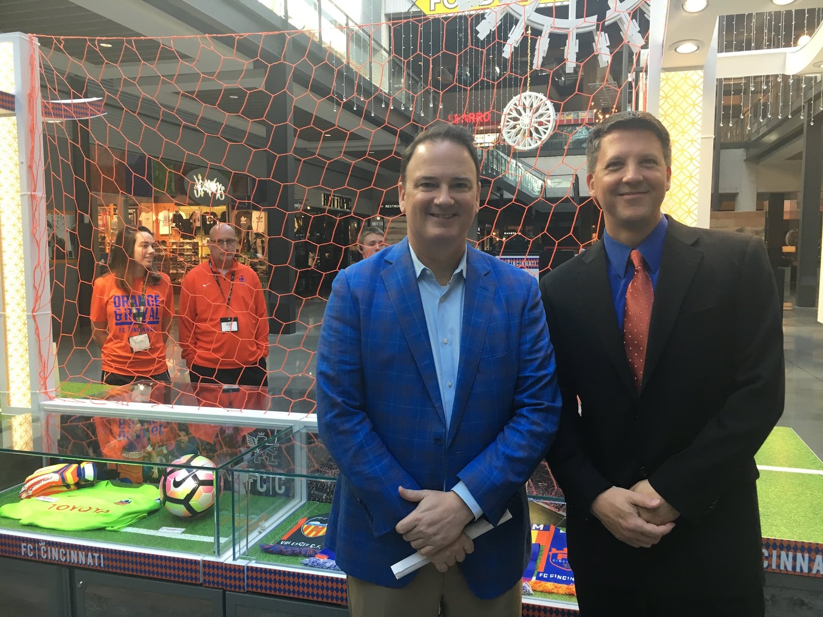 Jeff Berding, president and general manager of FC Cincinnati (left), and Kevin Cedik, general manager of Liberty Center (right) are pictured in front of a kiosk representing the soccer team inside of the Liberty Twp. development. The team and mixed-use development announced Tuesday a strategic partnership designed to create a buzz with fans in the Butler County area. WAYNE BAKER/STAFF