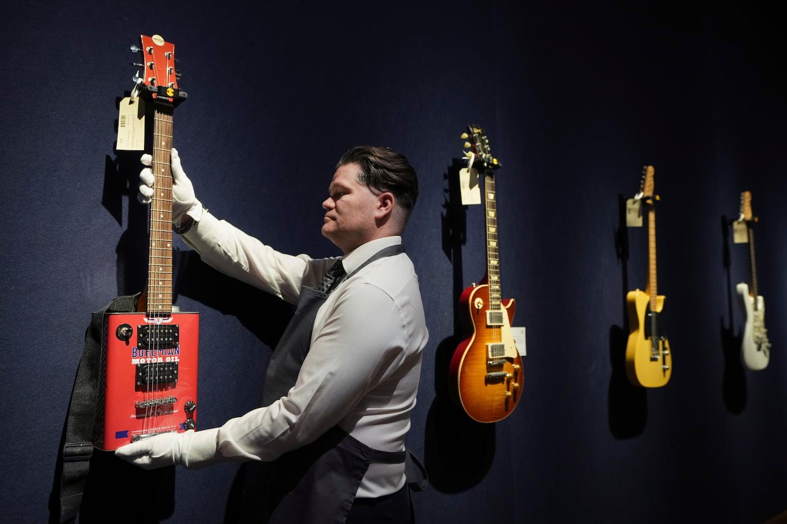 An art handler displays a Bohemian Guitars, Atlanta, Georgia, circa 2015, a novelty electric guitar in London, Tuesday, Jan. 14, 2025, ahead of the pre-sale exhibition of Jeff Beck The Guitar Collection at Christie's auction rooms in London. (AP Photo/Kirsty Wigglesworth)