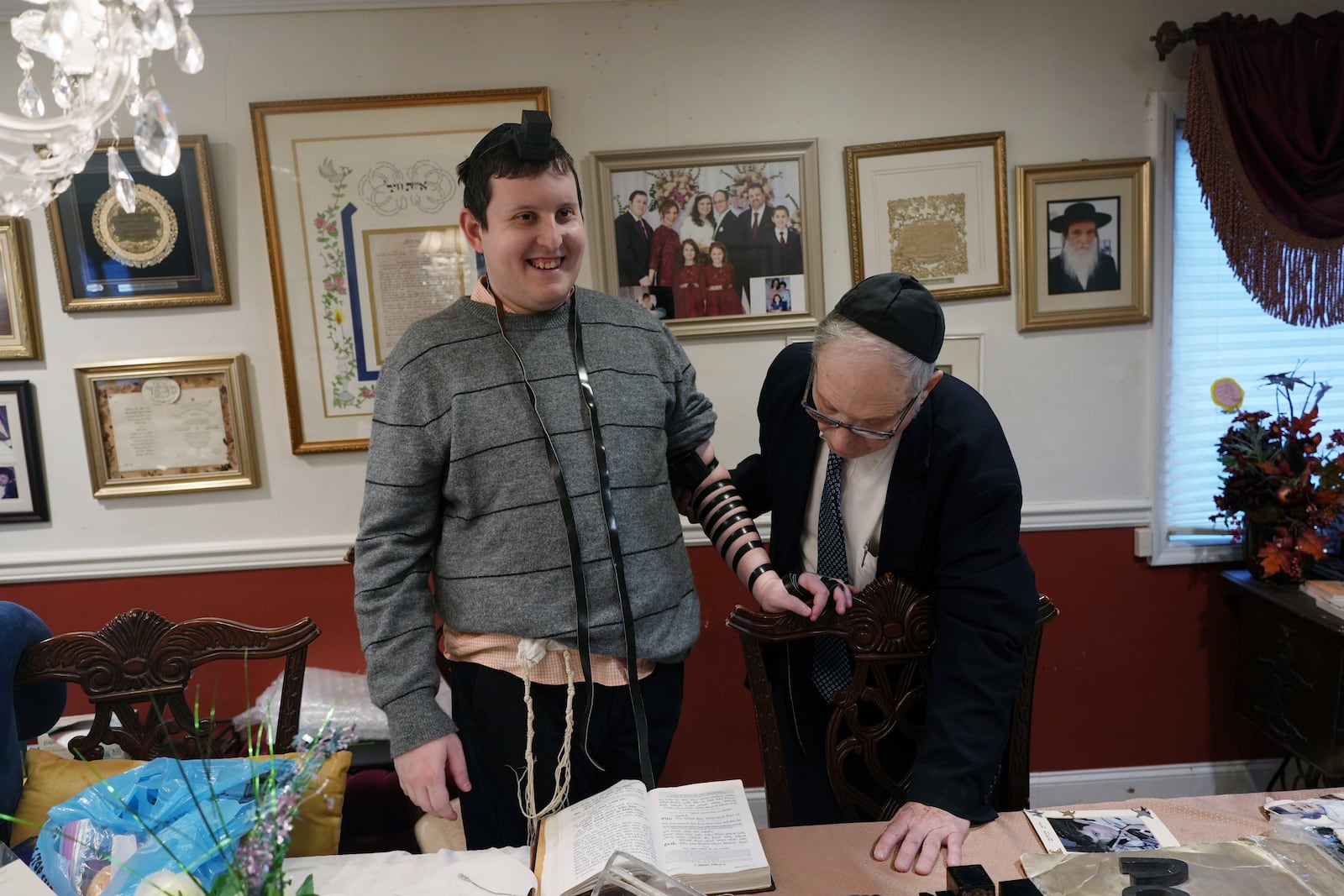 Dov Marcus smiles after wrapping the leather straps of tefillin to pray with his uncle, Chaim Orlan, in Teaneck, N.J., on Friday, Dec. 20, 2024. (AP Photo/Luis Andres Henao)