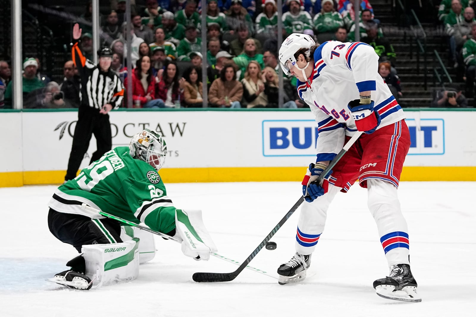 Dallas Stars goaltender Jake Oettinger (29) slaps the puck away on an attack by New York Rangers' Matt Rempe (73) in the second period of an NHL hockey game in Dallas, Friday, Dec. 20, 2024. (AP Photo/Tony Gutierrez)