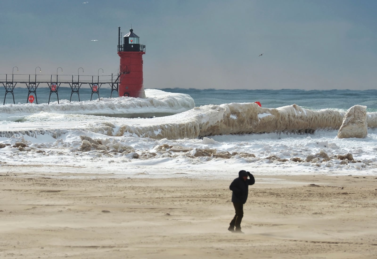 The sun breaks through overcast skies as ice forms along Lake Michigan and the South Haven Lighthouse Monday, Feb. 17, 2025, in South Haven, Mich. (Don Campbell/The Herald-Palladium via AP)