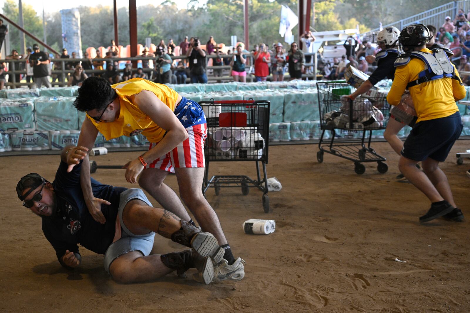 Yusuf Elshihibi, left, and Anthony Meda, second from left, compete in the Hurricane Party Prep: Grocery Aisle Brawl during the Florida Man Games, Saturday, March 1, 2025, in Elkton, Fla. (AP Photo/Phelan M. Ebenhack)