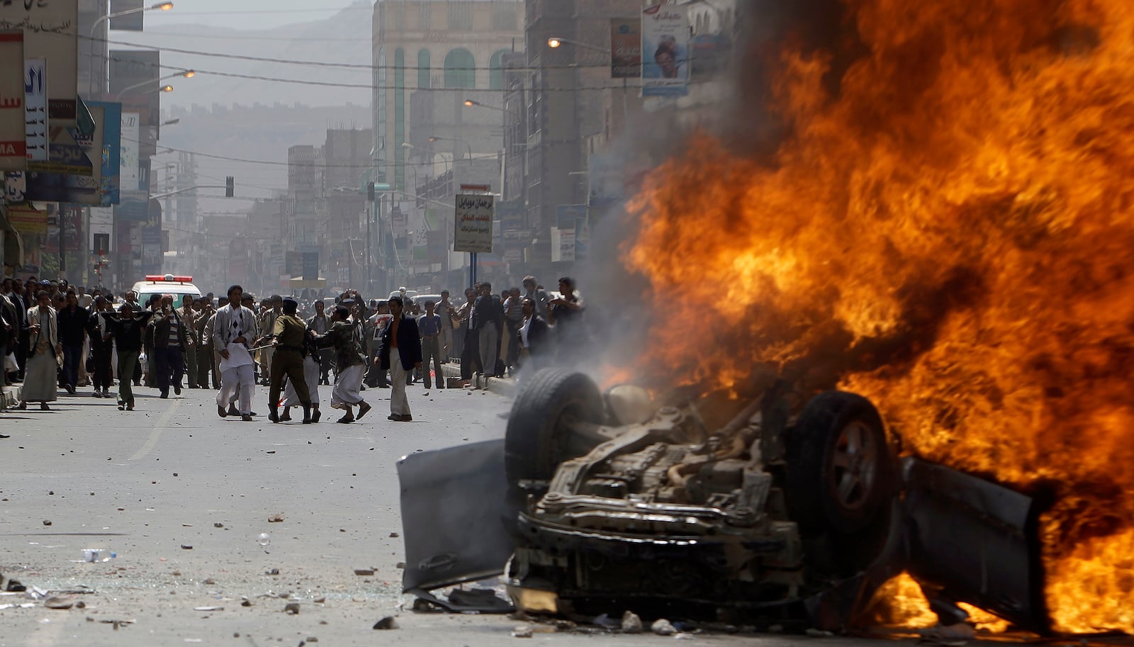 FILE - A Yemeni police officer stops supporters of the Yemeni government from reaching a vehicle set on fire by anti-government demonstrators during clashes in Sanaa, Yemen, on Feb. 22, 2011. (AP Photo/Muhammed Muheisen, File)