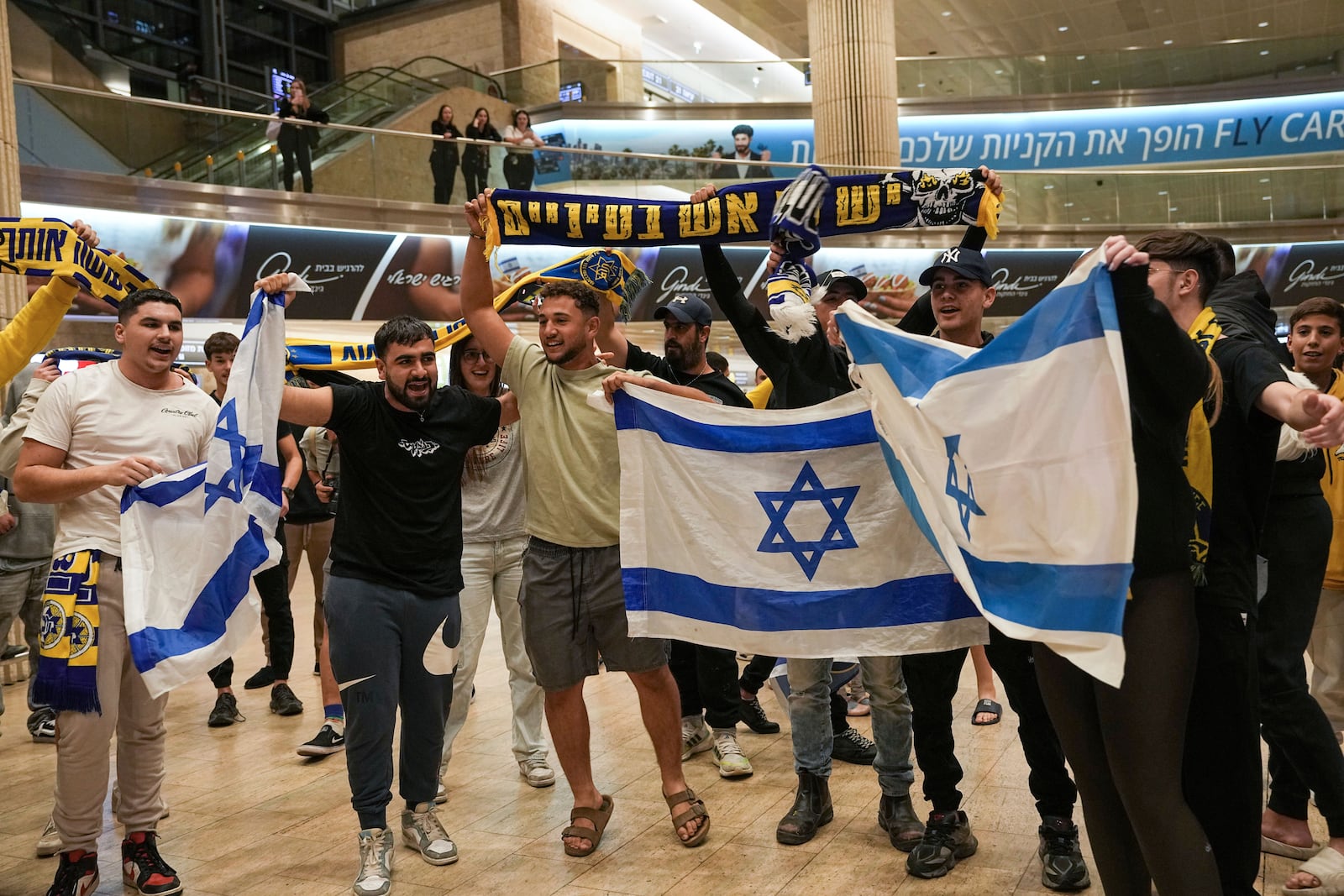 People welcome Maccabi Tel Aviv soccer fans as they arrive at Israel's Ben-Gurion International Airport on a flight from Amsterdam, where Israeli soccer fans were attacked following a match between the Israeli club and Ajax Amsterdam, in Lod, Israel, Friday, Nov. 8, 2024. (AP Photo/Tsafrir Abayov)