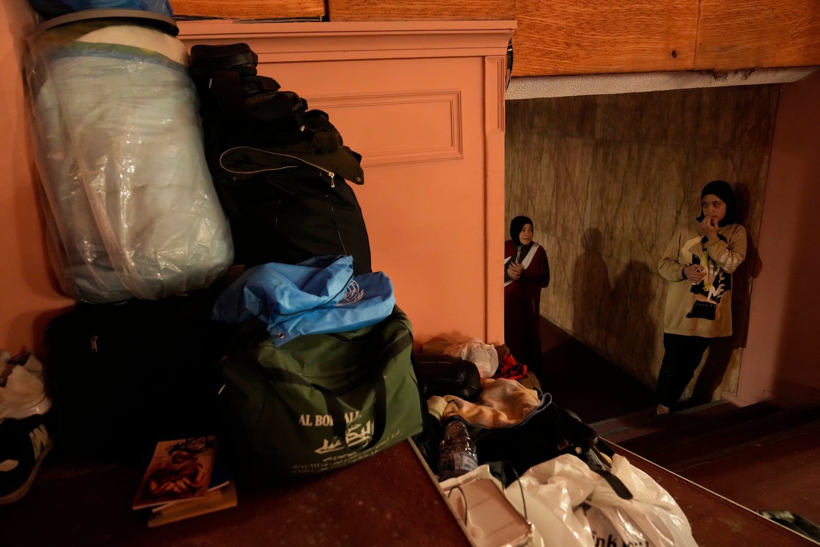 A girl who fled the ongoing Hezbollah-Israel war in south Lebanon, stands next to belongings inside one of Beirut's oldest and best known movie theatres, Le Colisee, in Beirut, Lebanon, Tuesday, Oct. 22, 2024. (AP Photo/Hussein Malla)