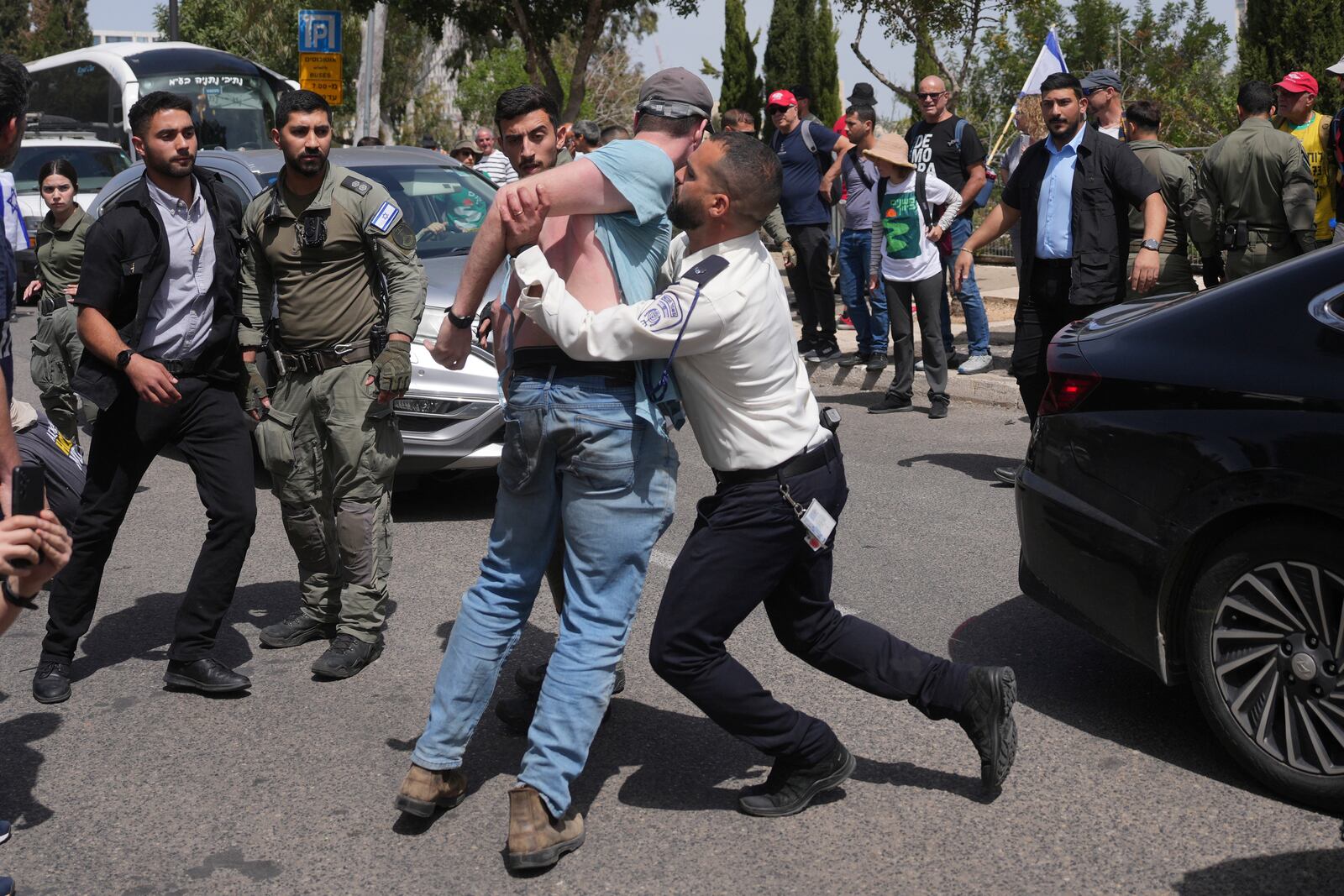 Police officers remove people as they block a road for the Israeli parliament during an anti-government protest after the Israeli cabinet passed a no-confidence vote against the country's attorney general, taking a first step toward her dismissal, in Jerusalem, Tuesday, March 25, 2025. (AP Photo/Ohad Zwigenberg)