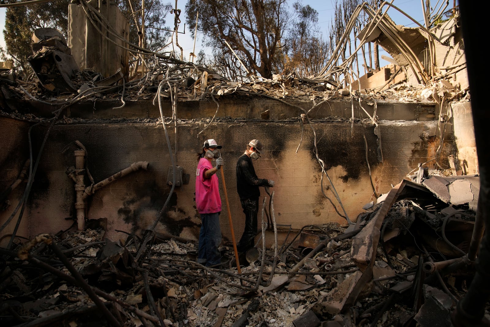 Kaegan Baron, left, and Oliver Braren sift through the home of Kaegan's mother after it was destroyed by the Palisades Fire in the Pacific Palisades neighborhood of Los Angeles, Saturday, Jan. 11, 2025. (AP Photo/John Locher)