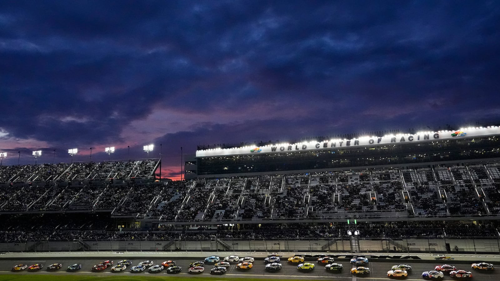 Drivers head into turn one as the sun sets over the grandstand during the NASCAR Daytona 500 auto race Sunday, Feb. 16, 2025, at Daytona International Speedway in Daytona Beach, Fla. (AP Photo/Chris O'Meara)