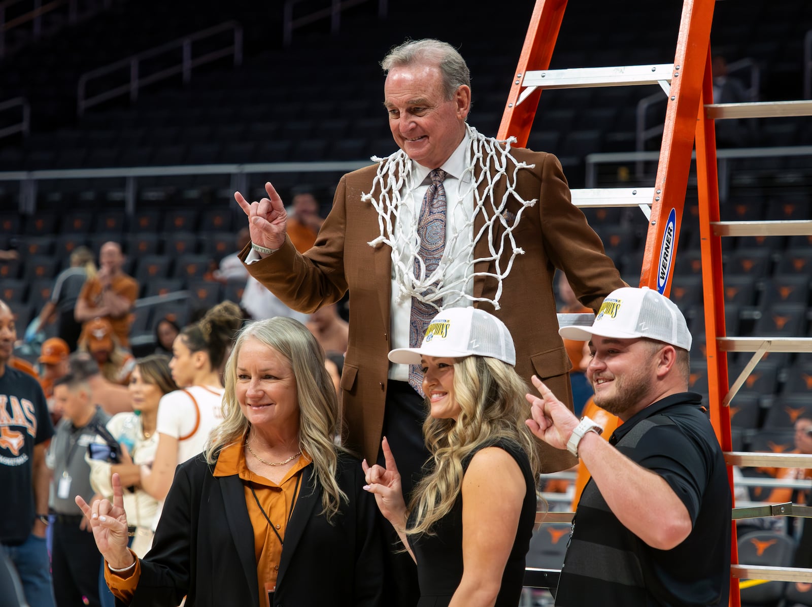 Texas Women's head basketball coach Vic Schaefer flashes the "Hook 'Em Horns" sign while wearing a net cut down after defeating Florida in an NCAA college basketball game, Sunday, March 2, 2025, in Austin, Texas. (AP Photo/Michael Thomas)