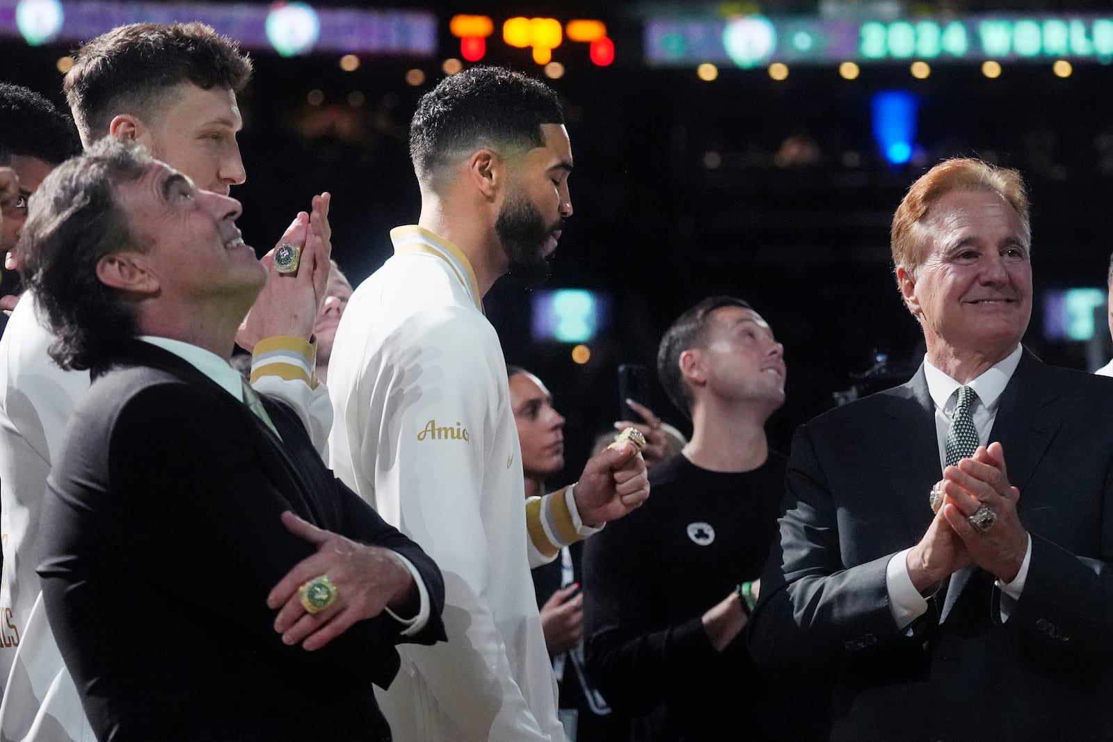 Boston Celtics forward Jayson Tatum, center, admires his ring as the 2024 World Championship banner is raised prior to an NBA basketball game against the New York Knicks, Tuesday, Oct. 22, 2024, in Boston. With Tatum are team owners Wyc Grousbeck, left, and Steve Pagliuca. (AP Photo/Charles Krupa)