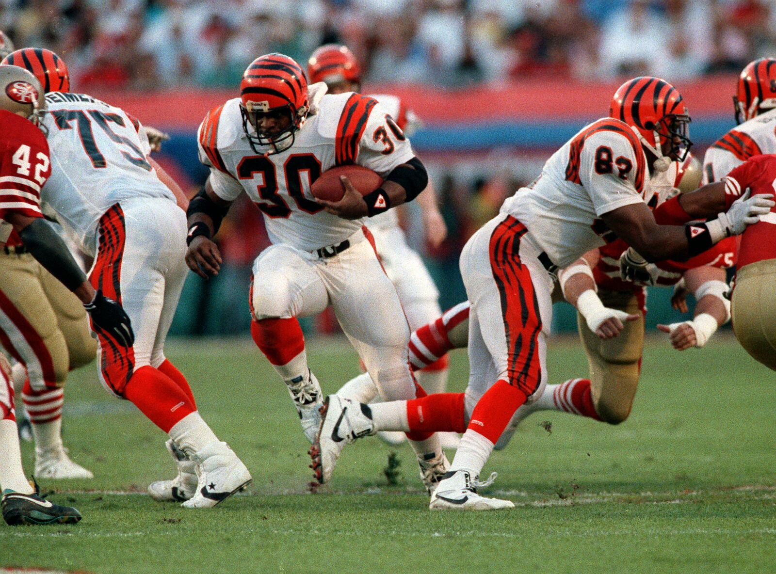 Cincinnati Bengals running back Ickey Woods (30) carries the ball as teammates Bruce Reimers (75) and Rodney Holman (82) block during first-quarter action against the San Francisco 49ers in Super Bowl XXIII in Miami, Fla. on Jan. 22, 1989. The Bengals lost 20-16. (AP Photo/Rusty Kennedy, File)