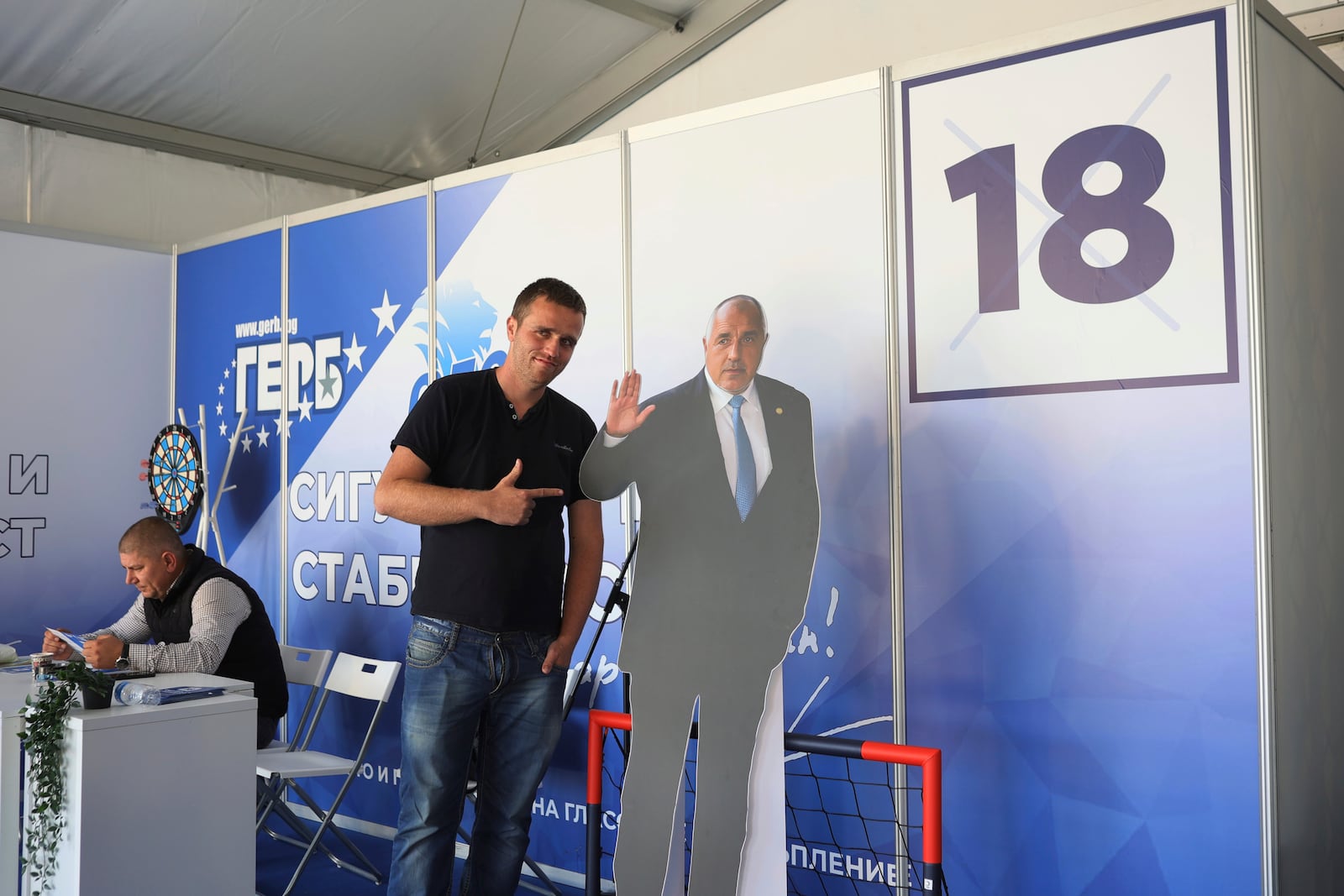 A GERB party supporter poses next to the party's leader Boyko Borissov in a cardboard portrait, Thursday, Oct. 24, 2024, in Sofia, as Bulgarians are called to cast ballots on Sunday in the seventh general elections in just over three years. (AP Photo/Valentina Petrova)