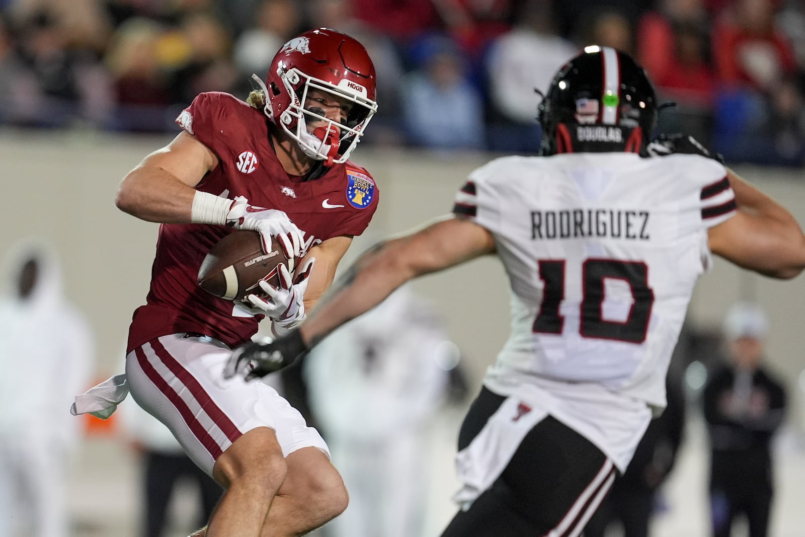 Arkansas wide receiver Isaac TeSlaa (4) makes a catch past Texas Tech linebacker Jacob Rodriguez (10) during the first half of the Liberty Bowl NCAA college football game Friday, Dec. 27, 2024, in Memphis, Tenn. (AP Photo/George Walker IV)