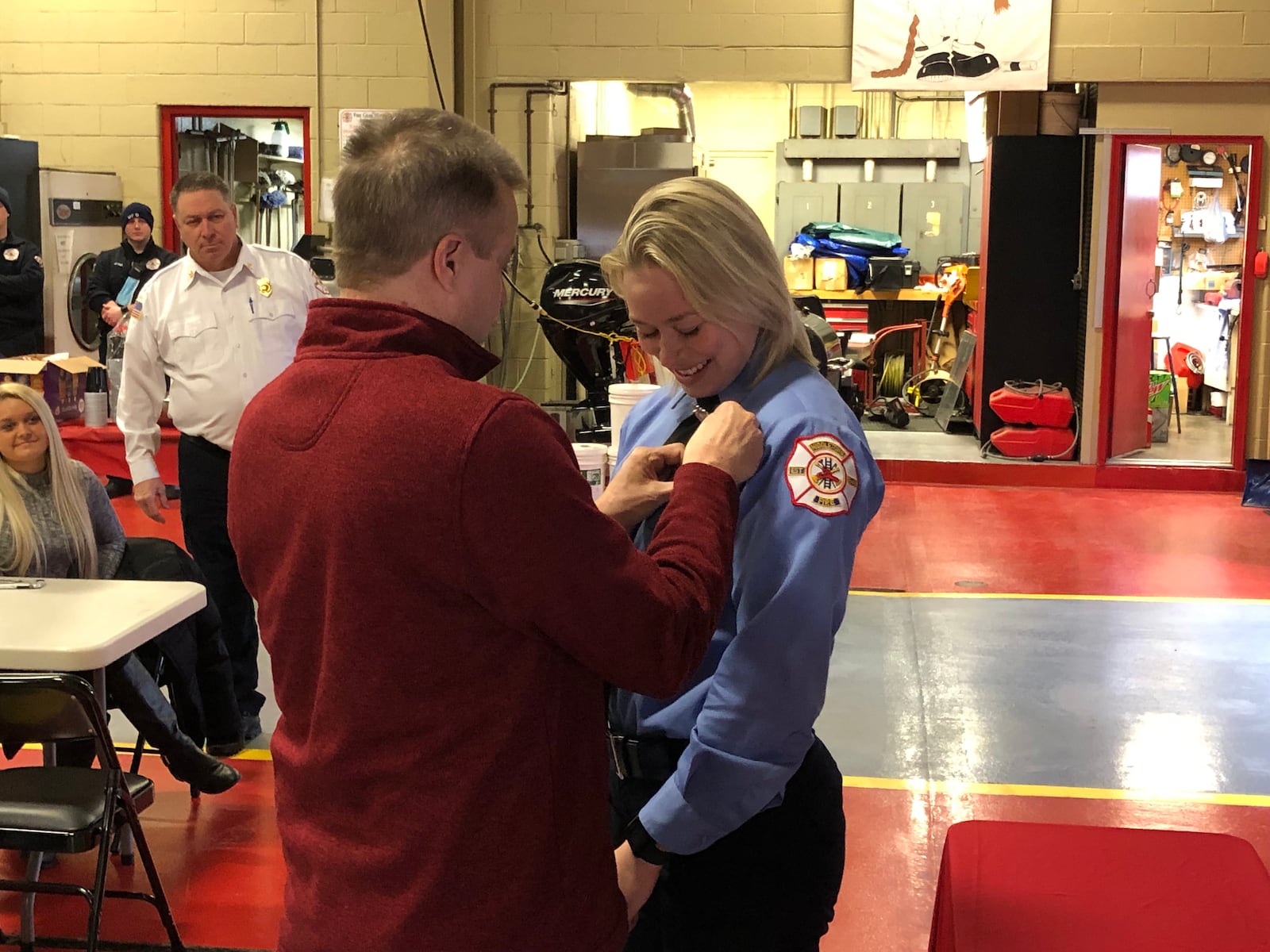 Celine Schank, 24, a 2015 Lakota West High School graduate, is pinned by her father, Thomas, Friday during a ceremony at Fire Headquarters. Fire Chief Paul Lolli looks on. RICK McCRABB/STAFF