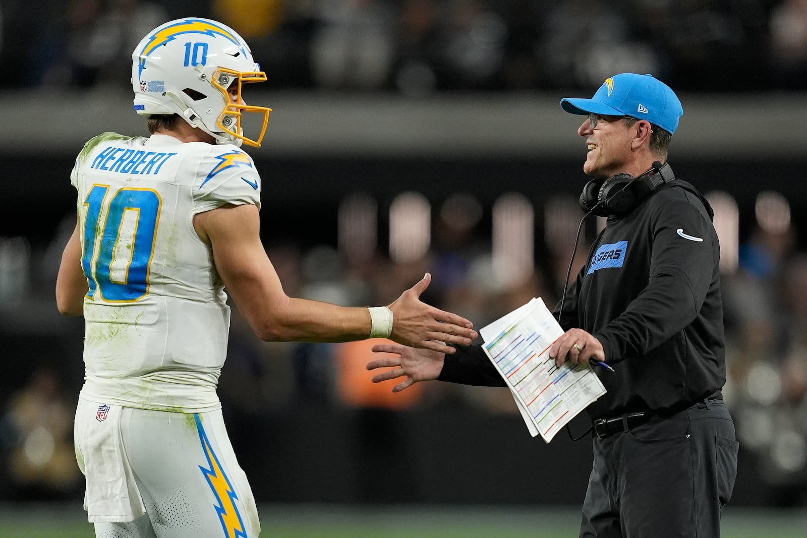 Los Angeles Chargers quarterback Justin Herbert (10) celebrates with head coach Jim Harbaugh during the second half of an NFL football game against the Las Vegas Raiders in Las Vegas, Sunday, Jan. 5, 2025. (AP Photo/John Locher)