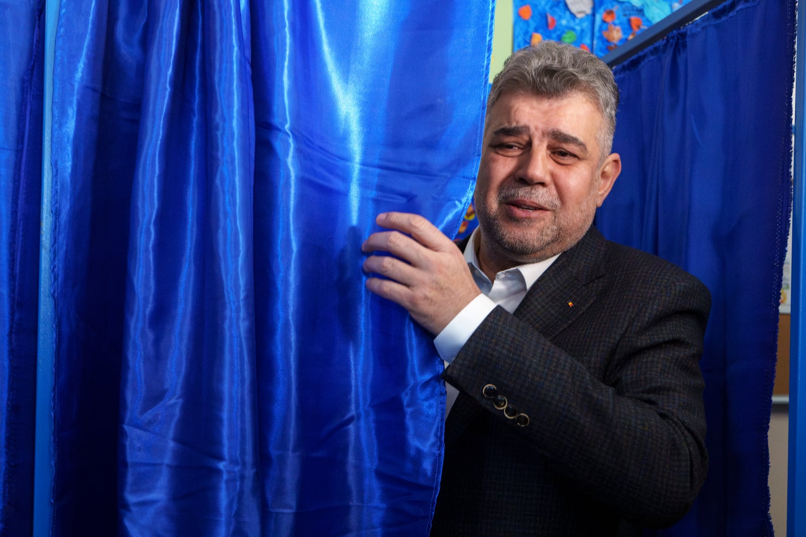 Romanian Prime Minister Marcel Ciolacu, the Social Democratic Party or PSD candidate in the country's presidential elections, peers from a voting cabin in Bucharest, Romania, Sunday, Nov. 24, 2024. (AP Photo/Vadim Ghirda)