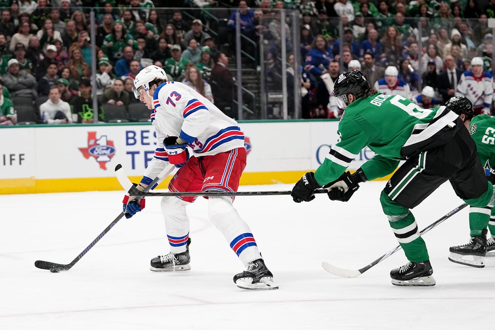 New York Rangers center Matt Rempe (73) controls the puck on an attack as Dallas Stars' Lian Bichsel, front right, attempts to break up the play in the second period of an NHL hockey game in Dallas, Friday, Dec. 20, 2024. (AP Photo/Tony Gutierrez)