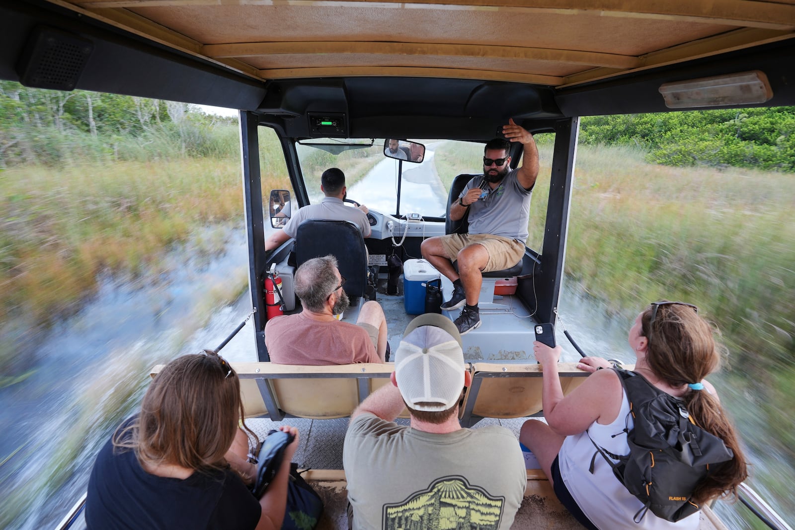 Naturalist tour guide Richard Petrosky speaks to visitors as fellow guide Juan Macias steers the tram through several inches of water covering long stretches of the path in the Shark Valley area of Florida's Everglades National Park, Fla., Wednesday, Nov. 20, 2024. (AP Photo/Rebecca Blackwell)