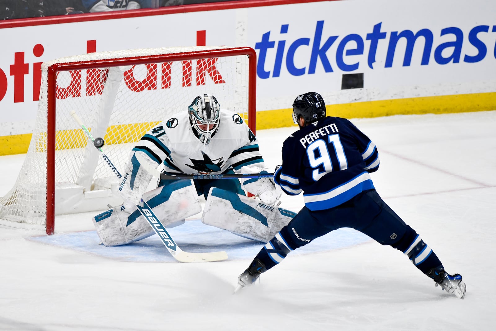 San Jose Sharks goaltender Vitek Vanecek (41) makes a save on Winnipeg Jets' Cole Perfetti (91) during the first period of an NHL hockey game in Winnipeg, Manitoba, Monday, Feb. 24, 2025. (Fred Greenslade/The Canadian Press via AP)