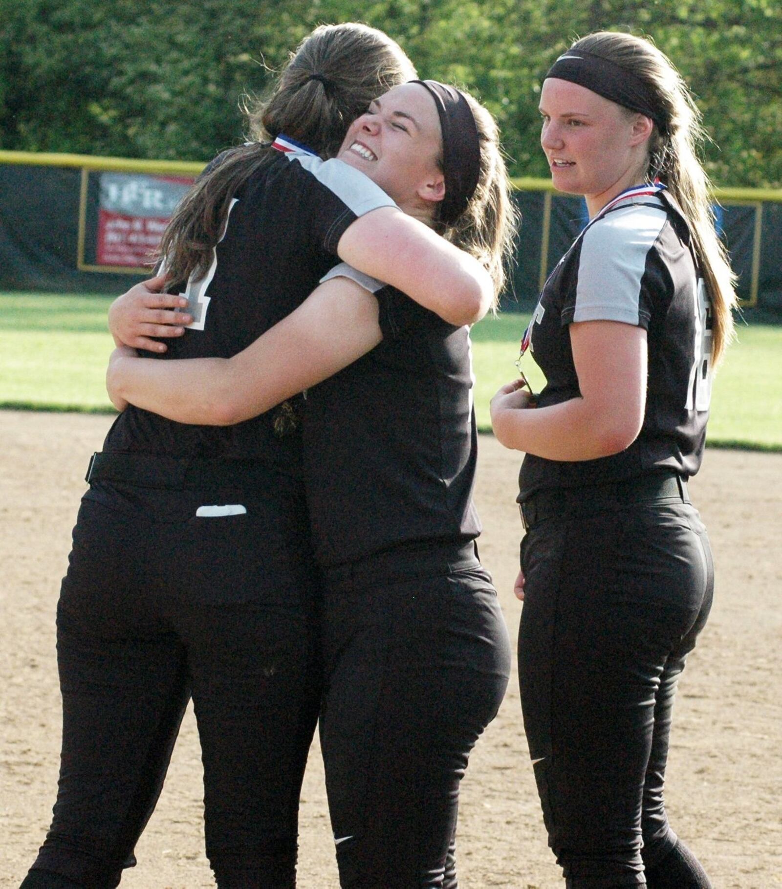 Lakota East’s Sydney Larson hugs teammate Abby Beckham (left) on Friday after the Thunderhawks defeated Lebanon 3-0 in a Division I district softball championship game at Centerville. RICK CASSANO/STAFF