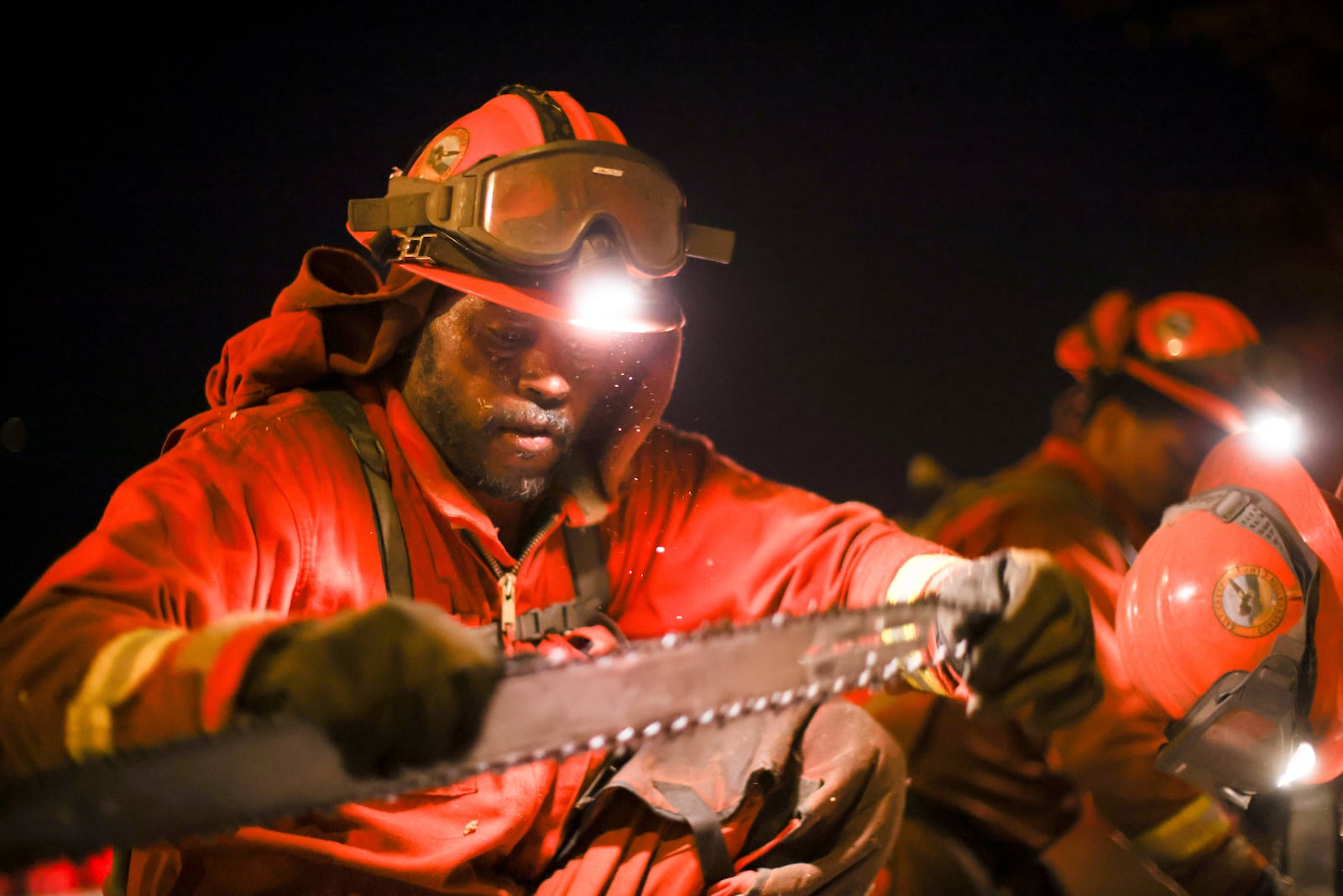 A California Department of Corrections hand crew works containment lines ahead of the Palisades Fire Tuesday, Jan. 14, 2025 in Santa Monica, Calif. (AP Photo/Ethan Swope)